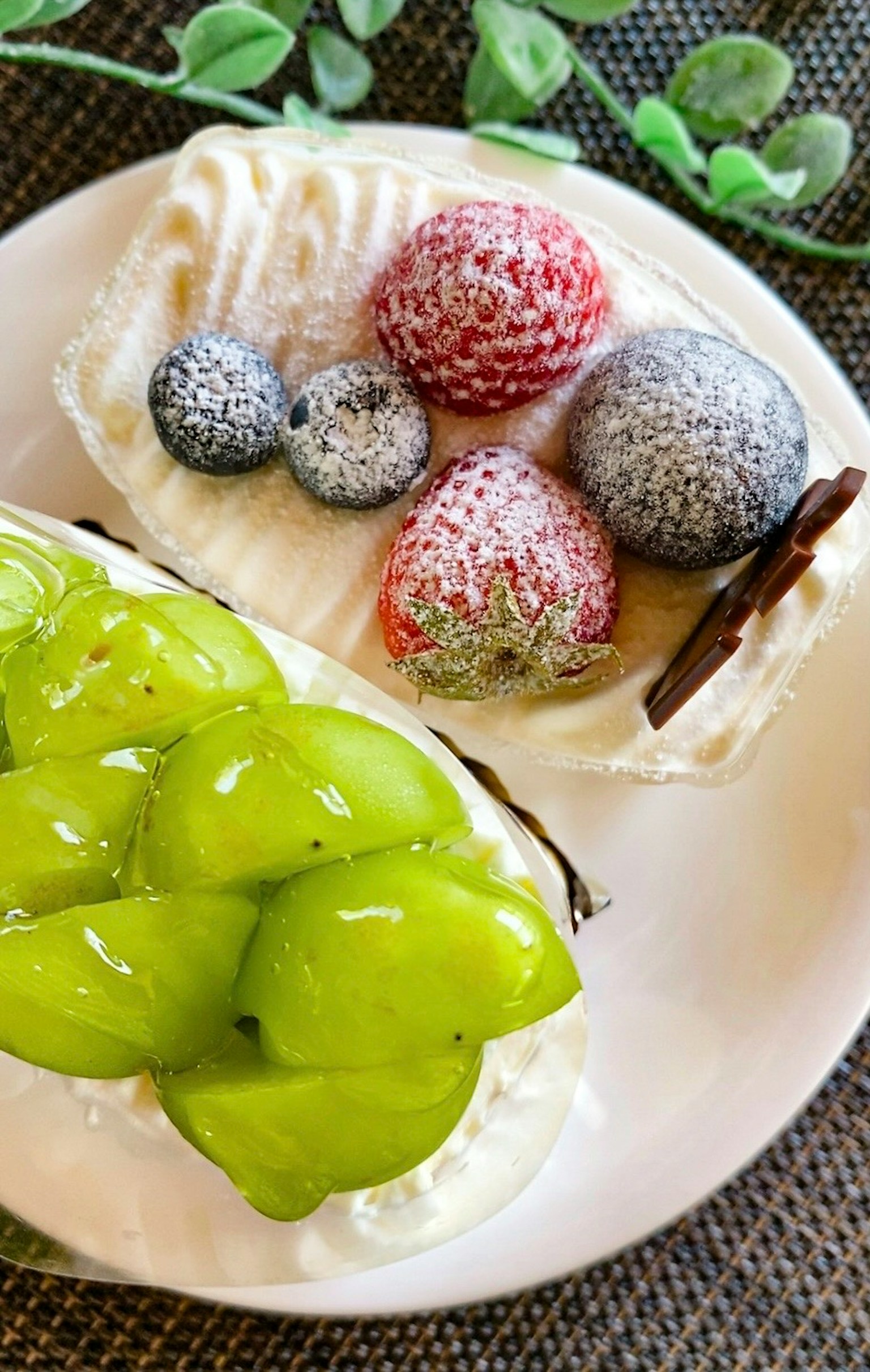 クリームがトッピングされたフルーツケーキのスライスには新鮮なベリーとグリーンのフルーツが飾られている