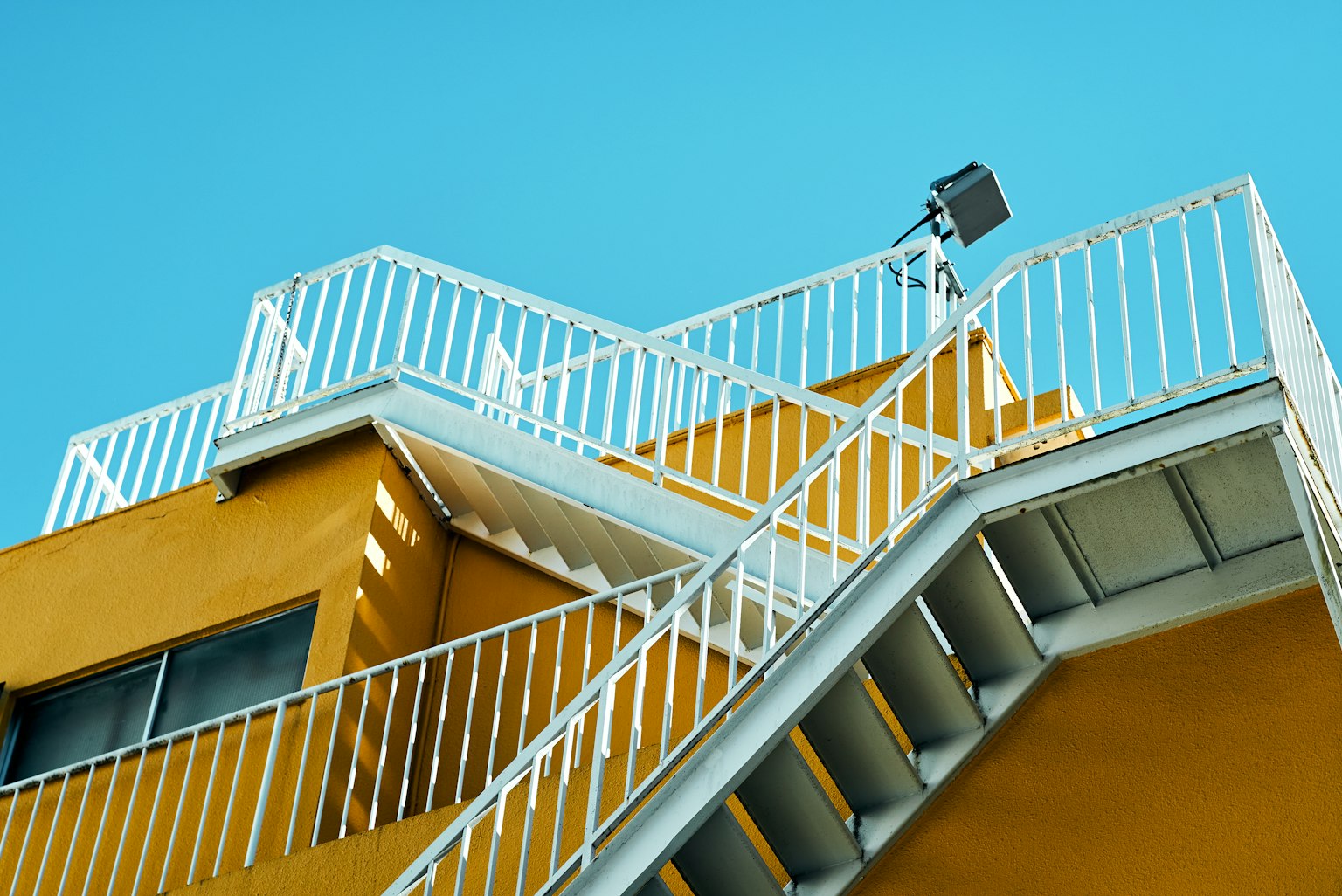 Vista di un edificio giallo con ringhiere e scale bianche