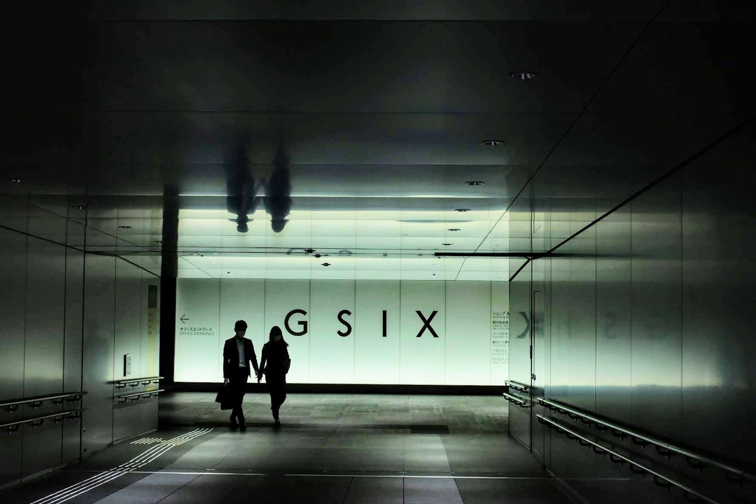 เงาของคนสองคนในอุโมงค์มืดที่มีป้าย GSIX สว่าง