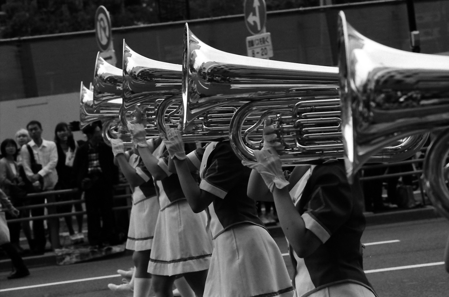 Photo en noir et blanc de filles tenant des tubas lors d'un défilé