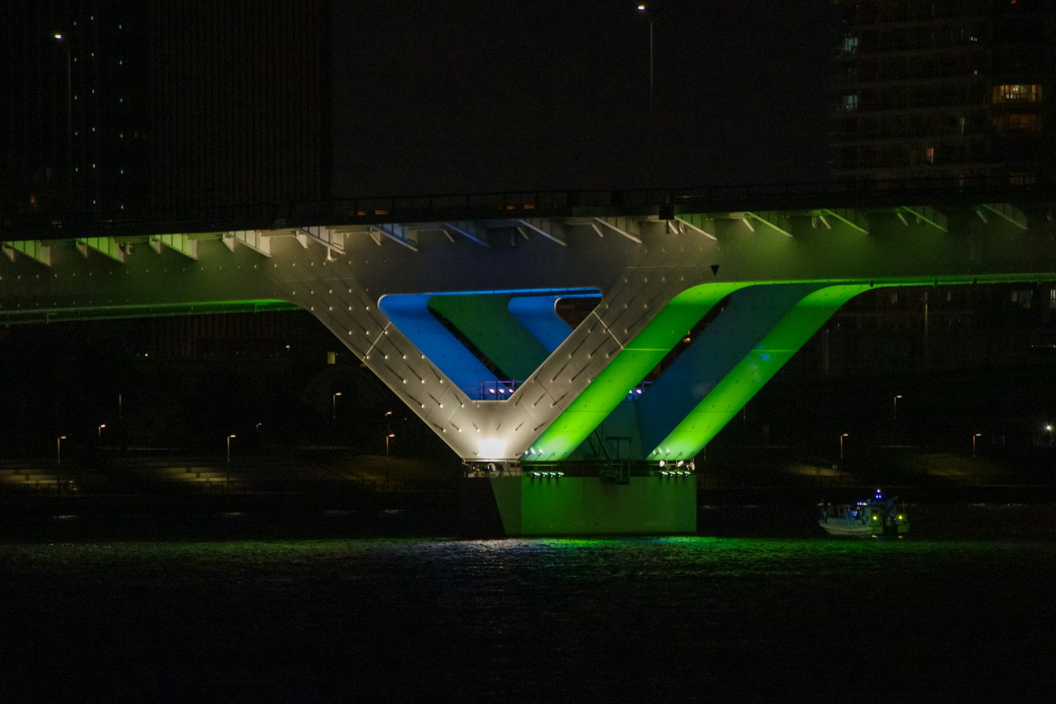 Struttura di ponte moderna illuminata con luci verdi e blu di notte