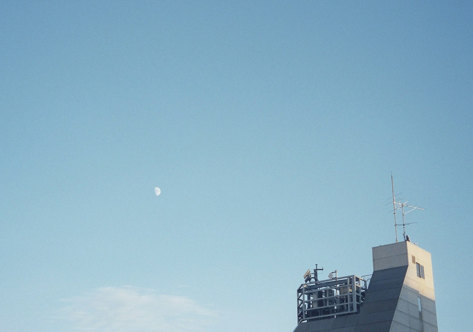 Edificio contra un cielo azul claro con una luna visible