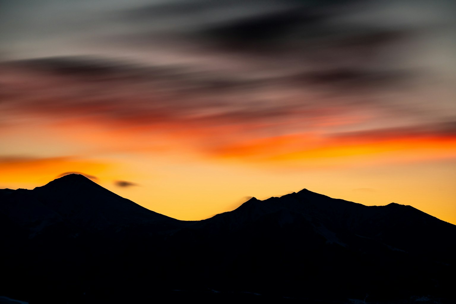 Montagnes en silhouette contre un ciel de coucher de soleil vibrant