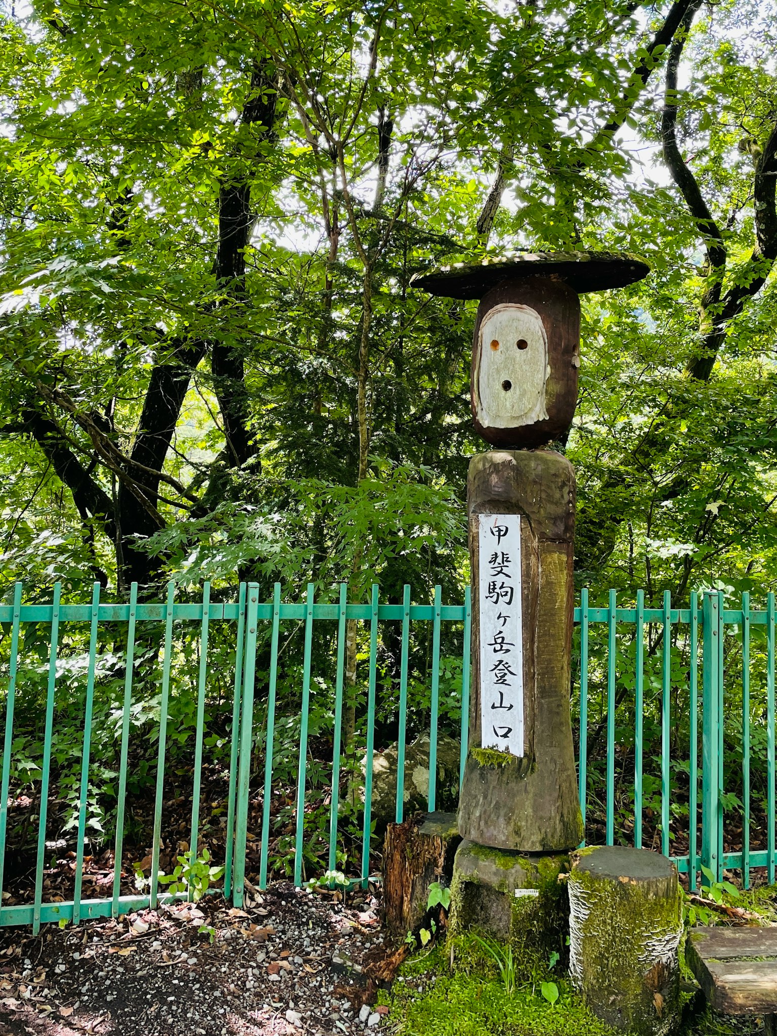 숲 속의 나무 조각상과 일본어로 새겨진 표지판
