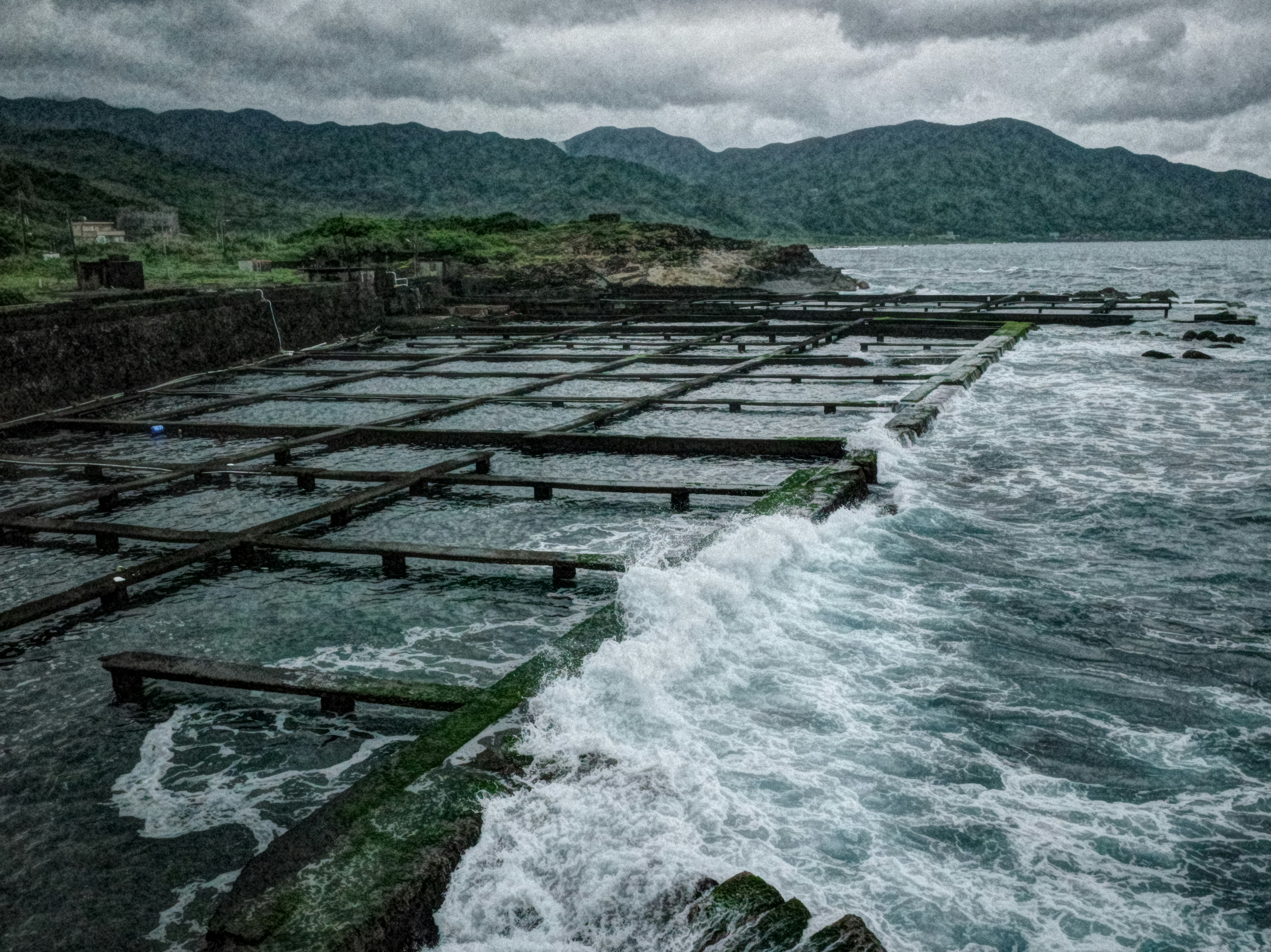 台湾の海岸に並ぶ養殖いかだと波しぶきのある風景