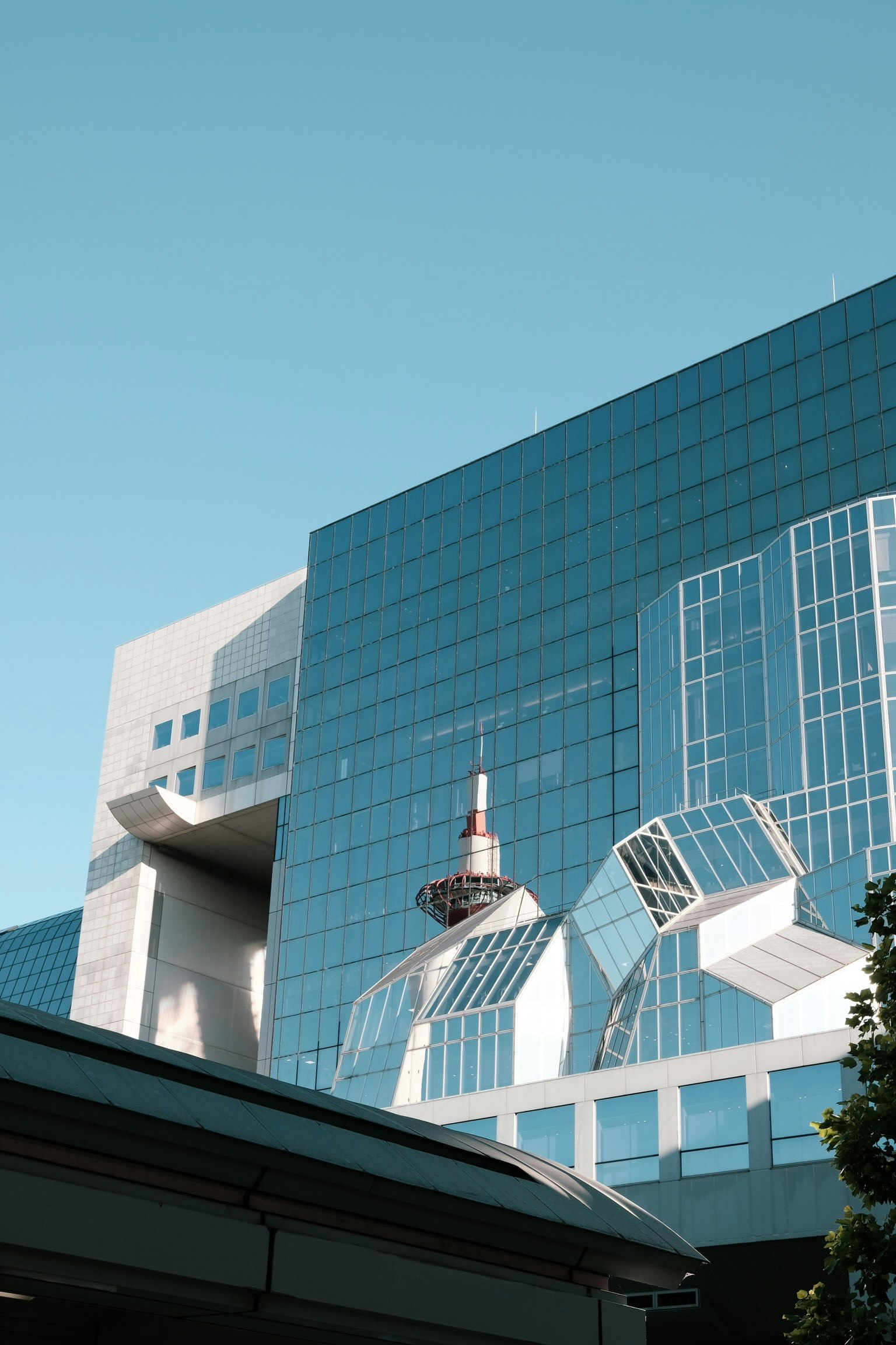 Modern building facade under blue sky featuring reflective glass and unique shapes