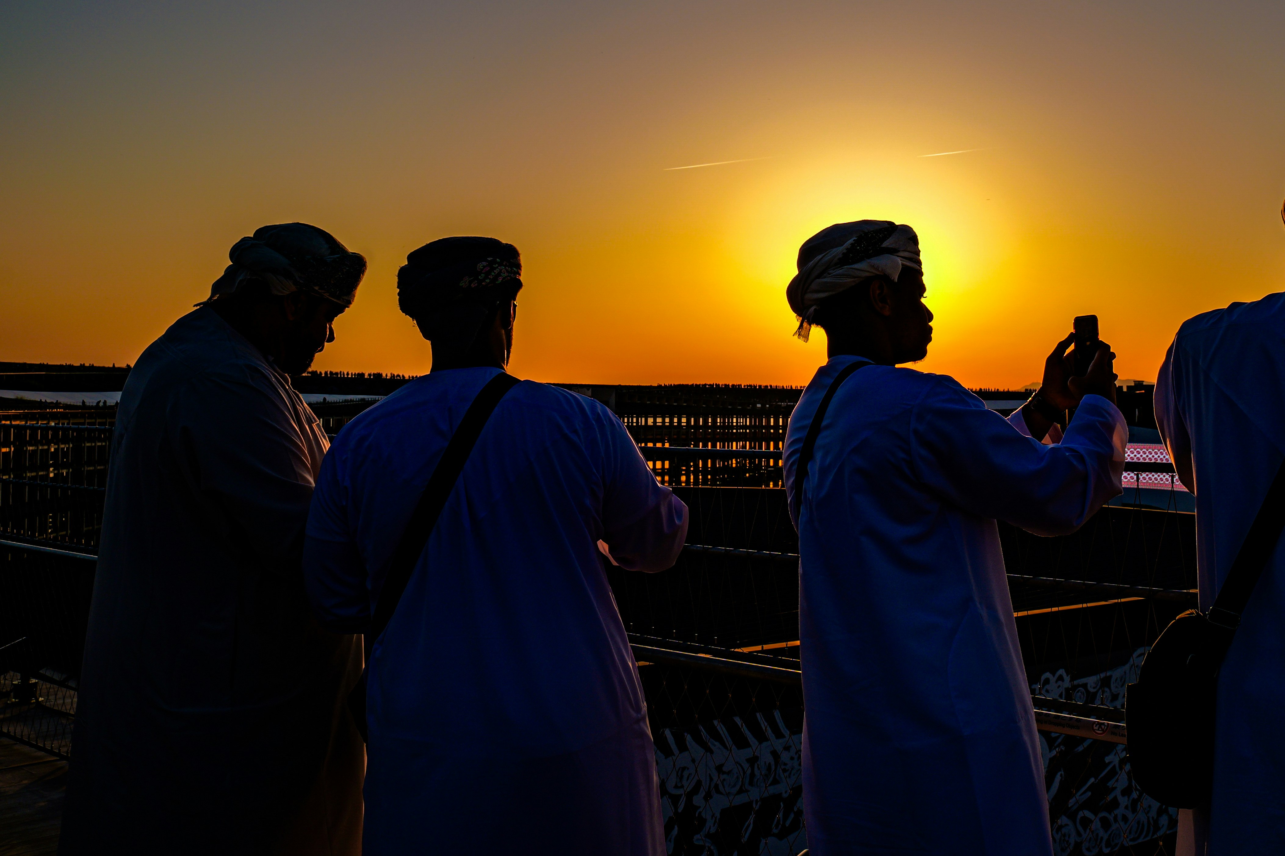 Silhouetted people against a sunset sky