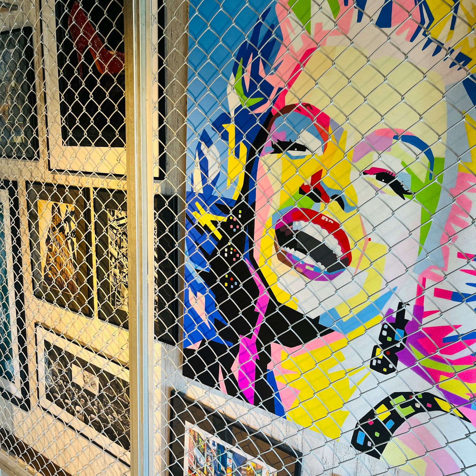 Colorful portrait of Marilyn Monroe surrounded by a wire fence in an art display