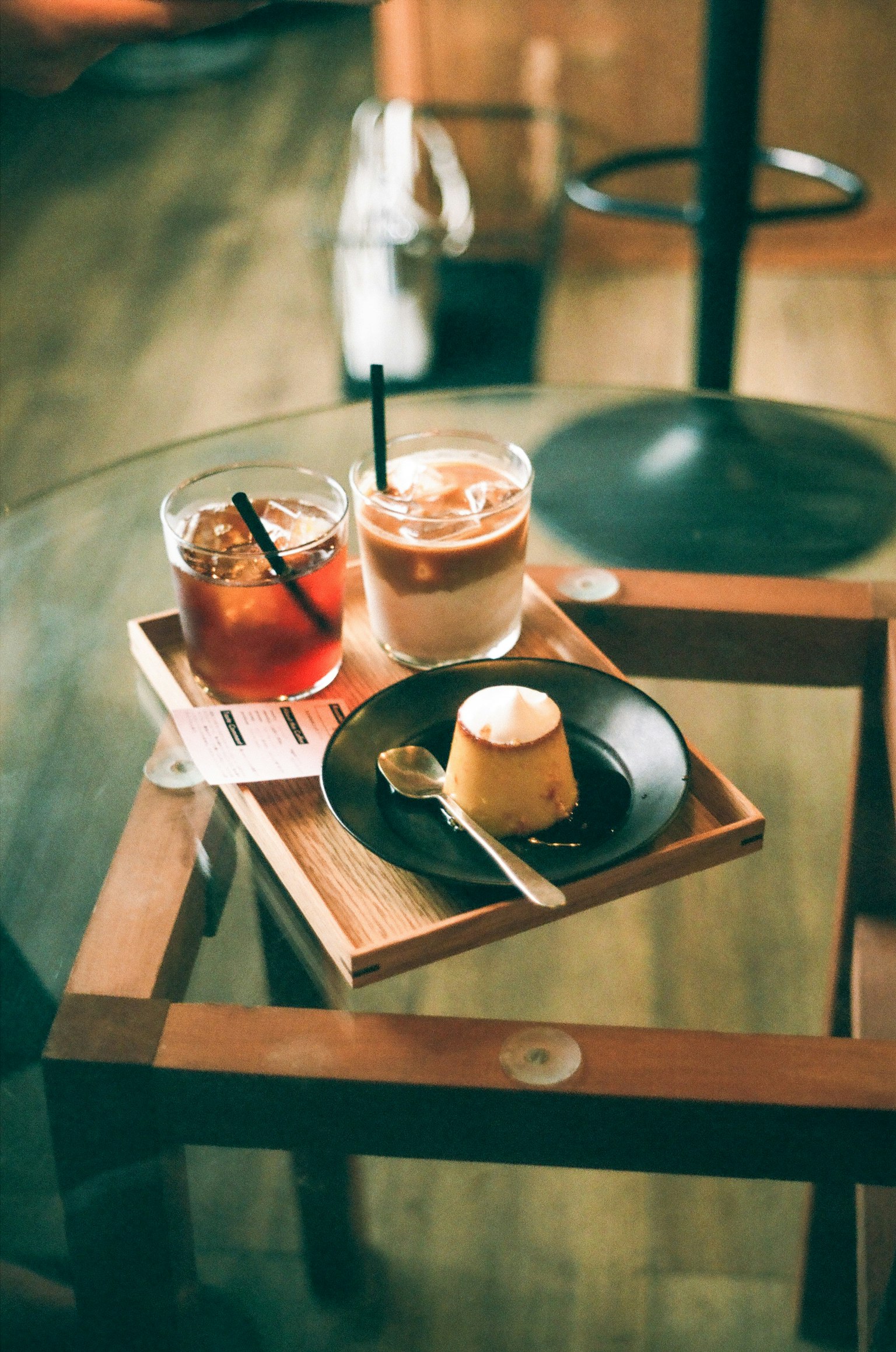 Due bicchieri di caffè freddo e tè con un budino su un vassoio di legno