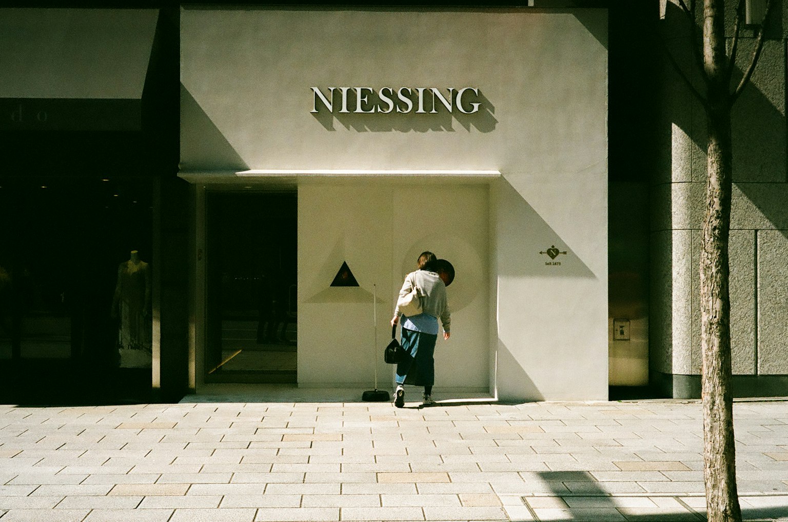 一名女性站在一間現代商店前，商店名為Niessing