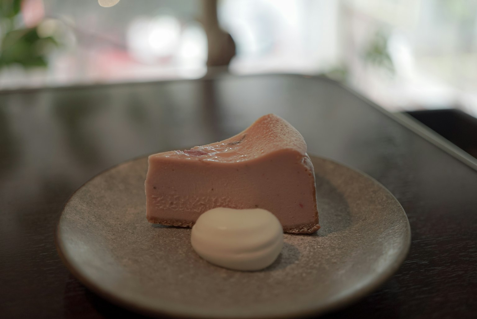 Ein rosa Dessert auf einem runden Teller, begleitet von einem Klecks cremiger Schlagsahne
