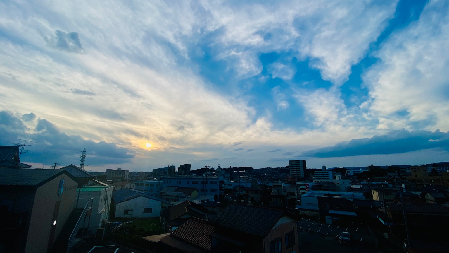 Vue panoramique d'un ciel bleu et de nuages au-dessus d'un quartier résidentiel au coucher du soleil