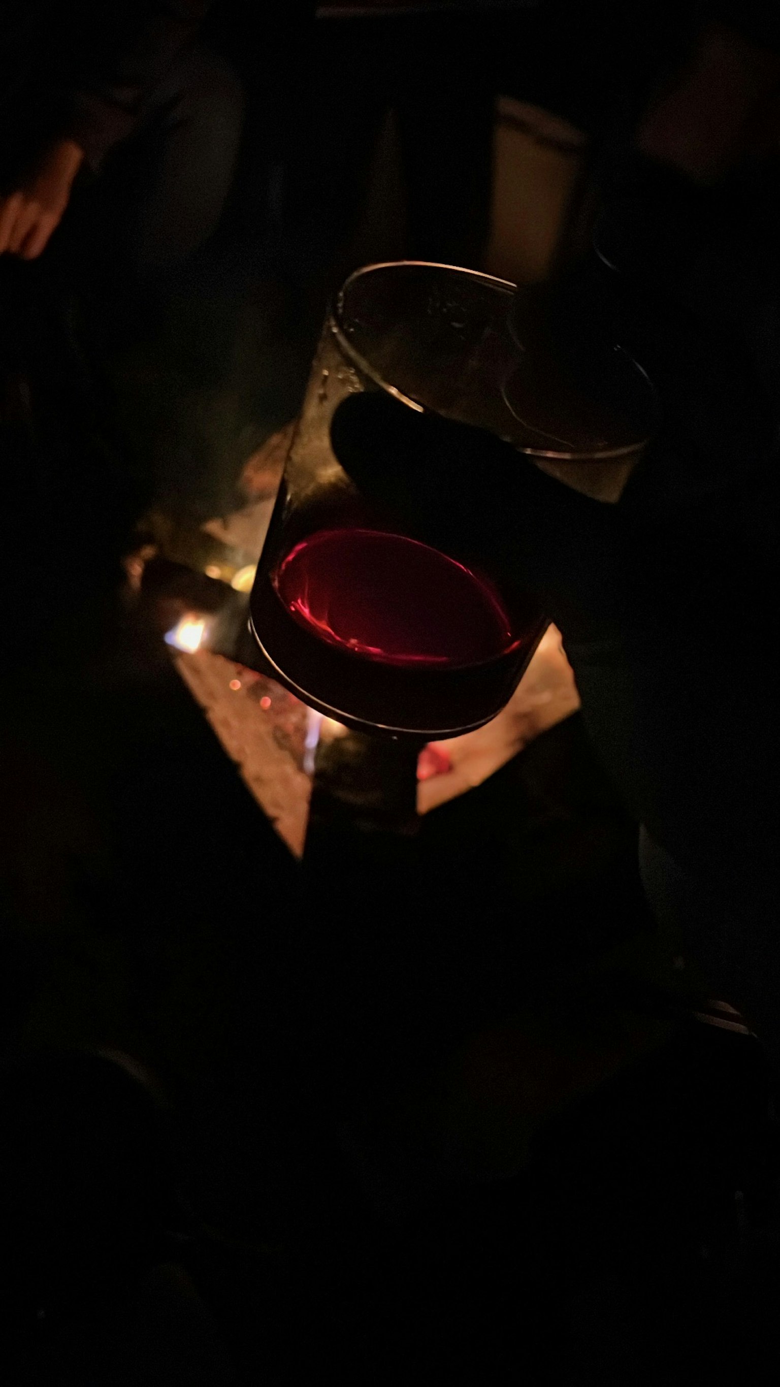 Vaso de vino tinto iluminado por una fogata en un entorno oscuro