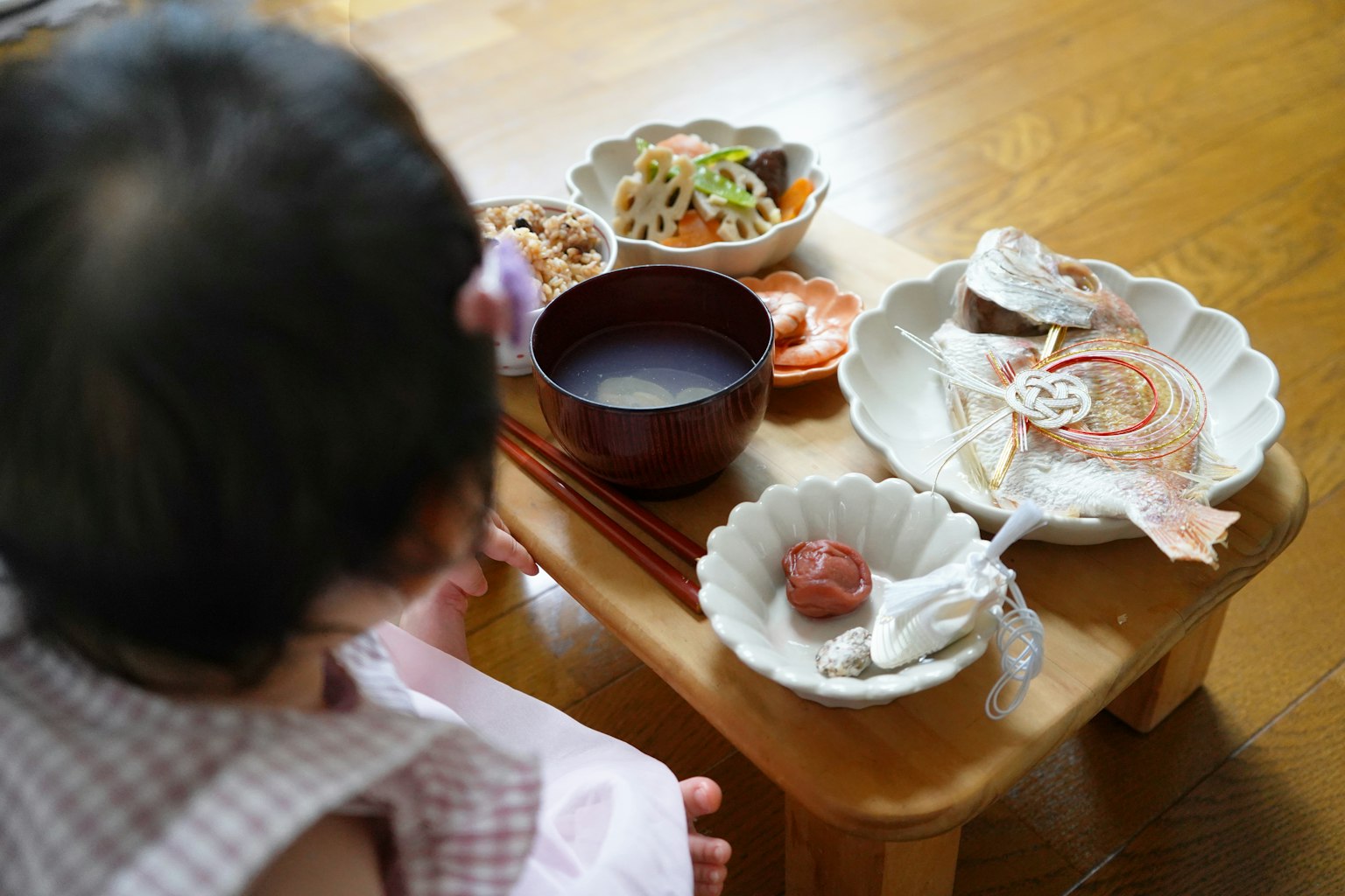 Ein Kind sitzt an einem Tisch mit einem traditionellen japanischen Essen