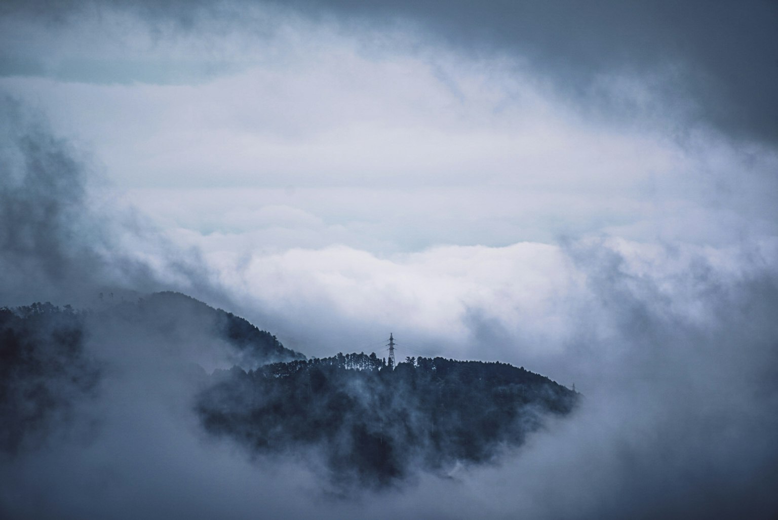 Nebeliger Berglandschaft mit einem Turm über den Wolken