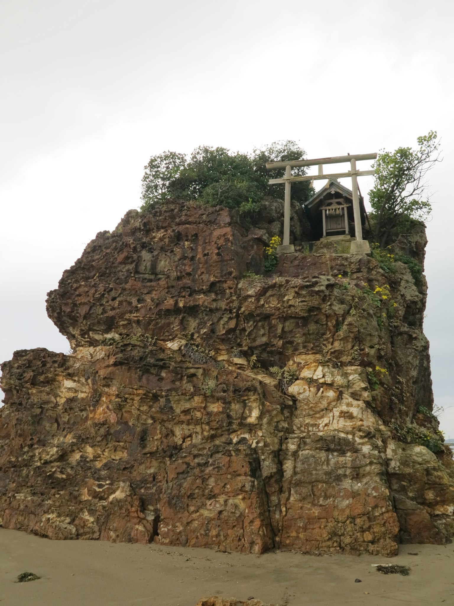 A shrine-like structure atop a rocky outcrop with greenery surrounding it
