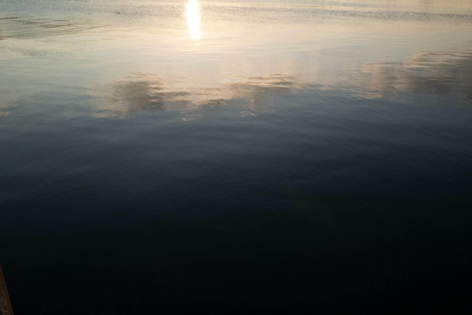 Superficie de agua tranquila reflejando la luz del atardecer