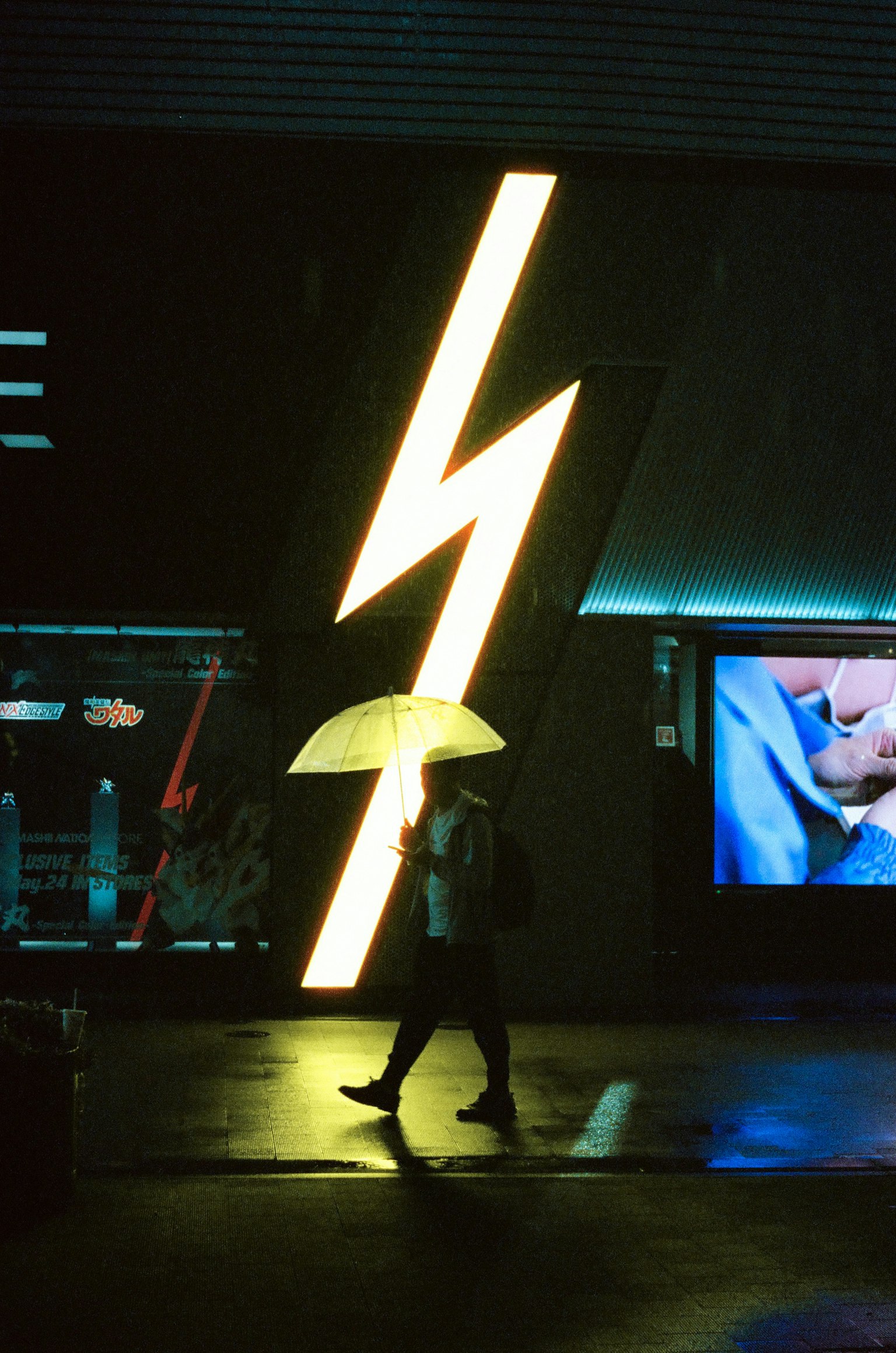 Persona che cammina con un ombrello davanti a un'insegna al neon a forma di fulmine