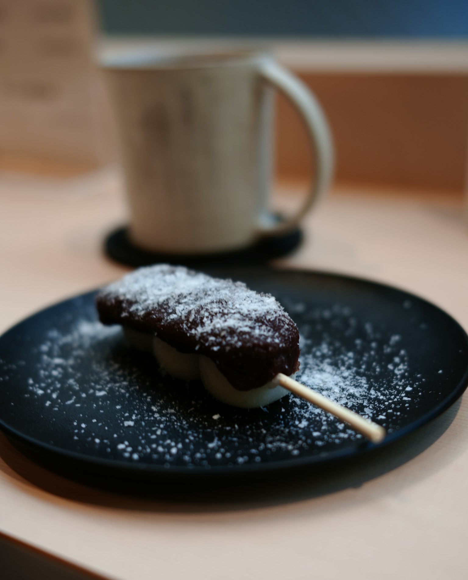 Un dolce su un piatto nero cosparso di zucchero a velo
