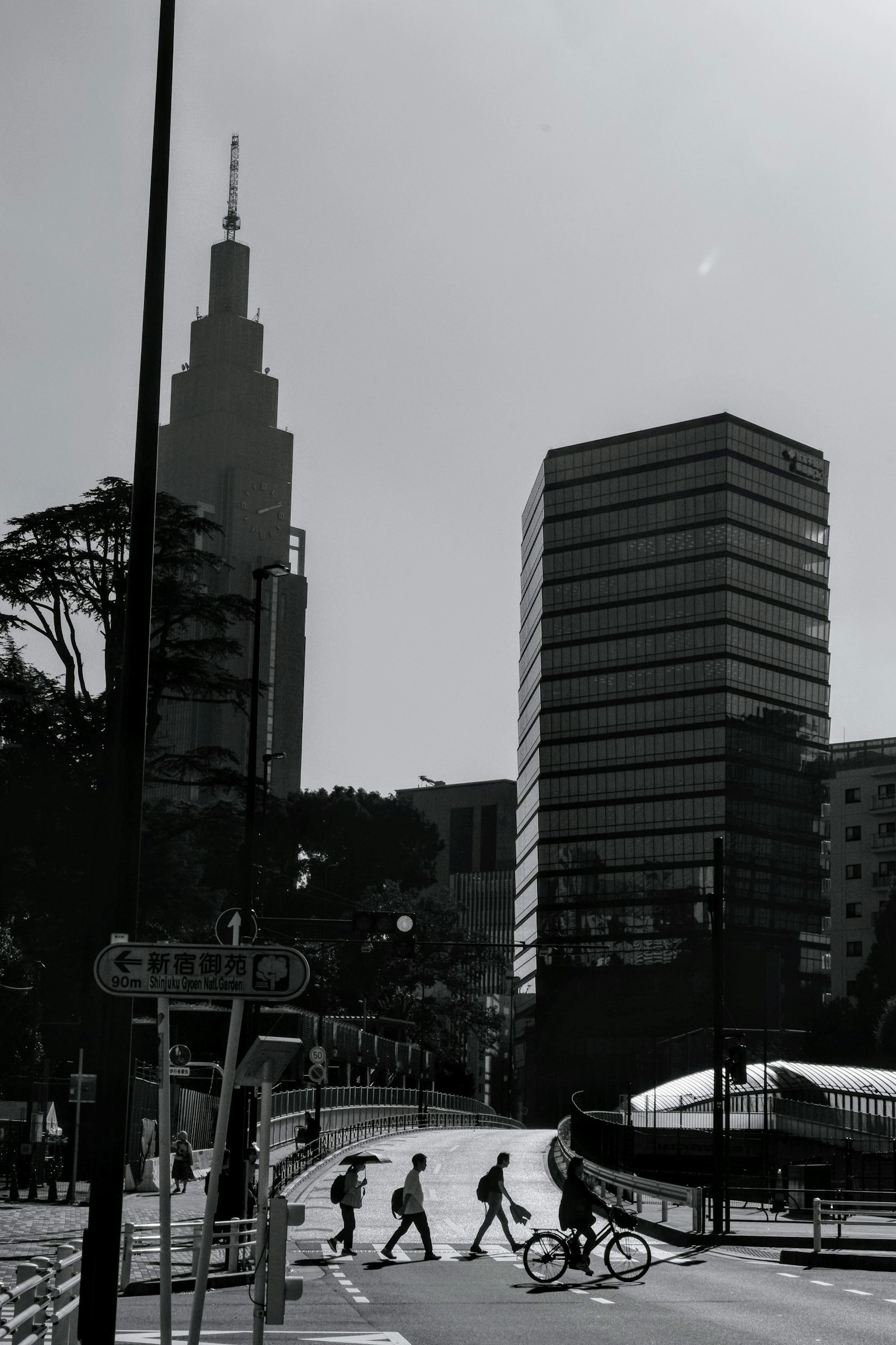 Black and white cityscape featuring pedestrians crossing a street with skyscrapers in the background