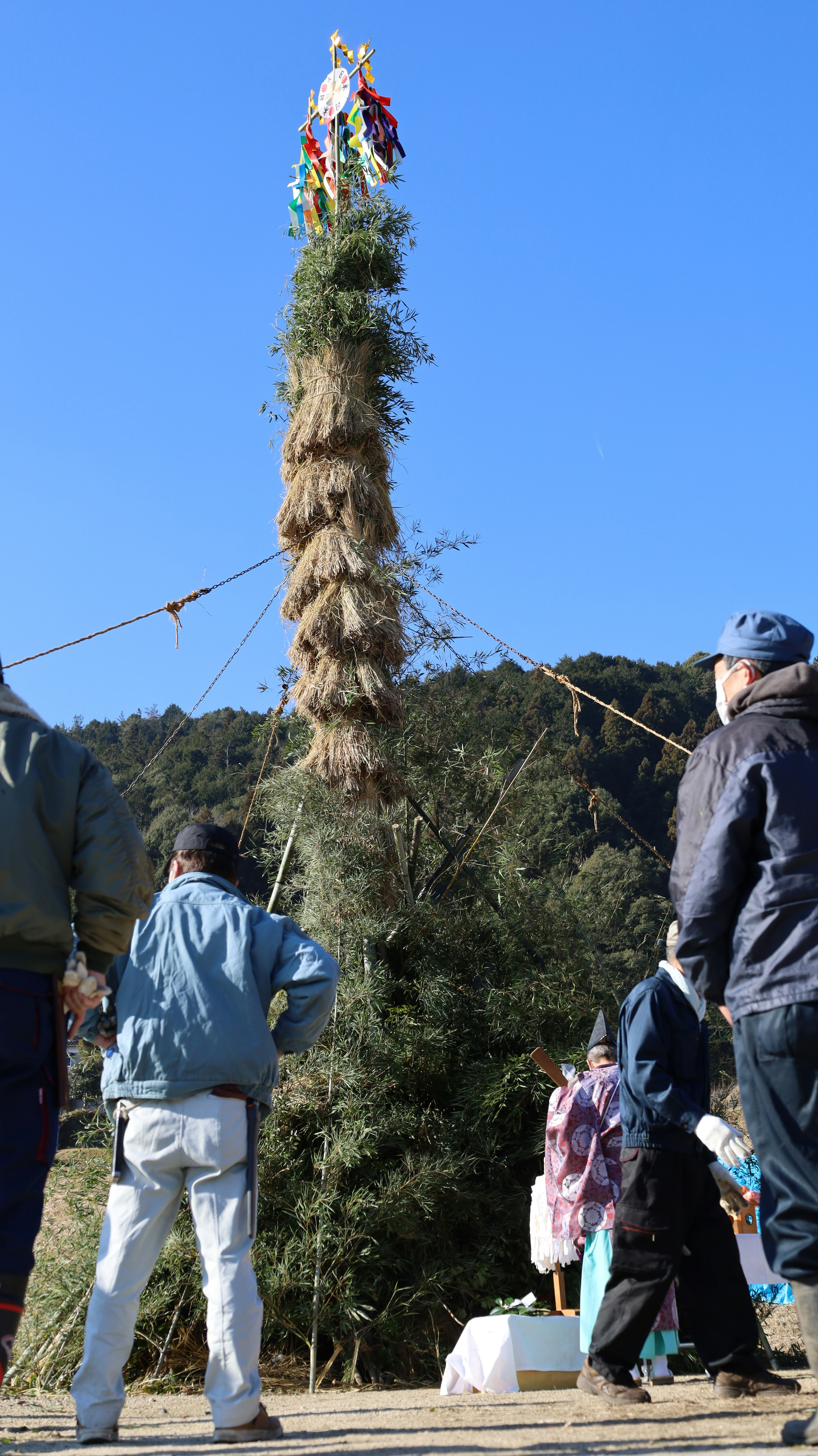 outdoor scene with people tying decorations under a blue sky and mountains