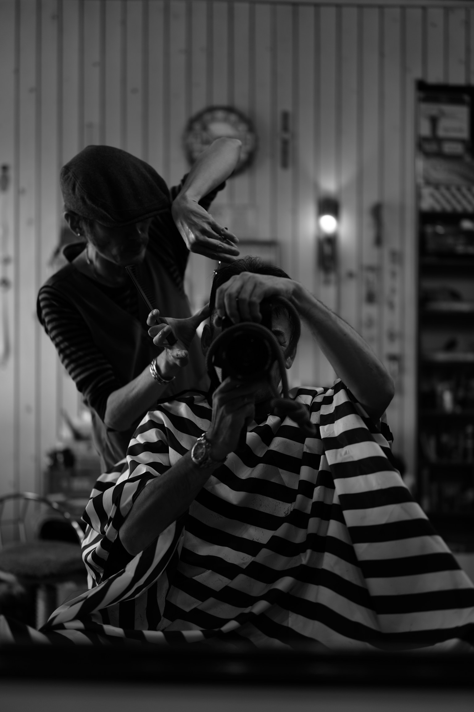 美容室で髪を切っている人と鏡越しの自分を映したモノクロ写真