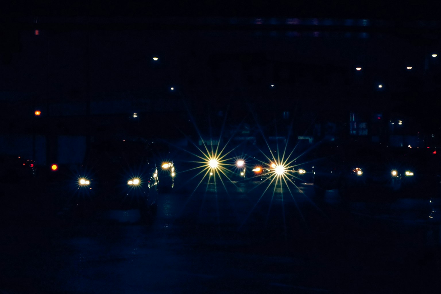 Autos auf einer Stadtstraße bei Nacht mit hellen Scheinwerfern