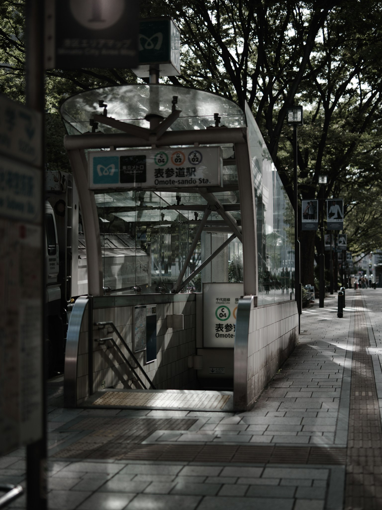 Entrée de métro avec un ascenseur en verre entouré d'arbres