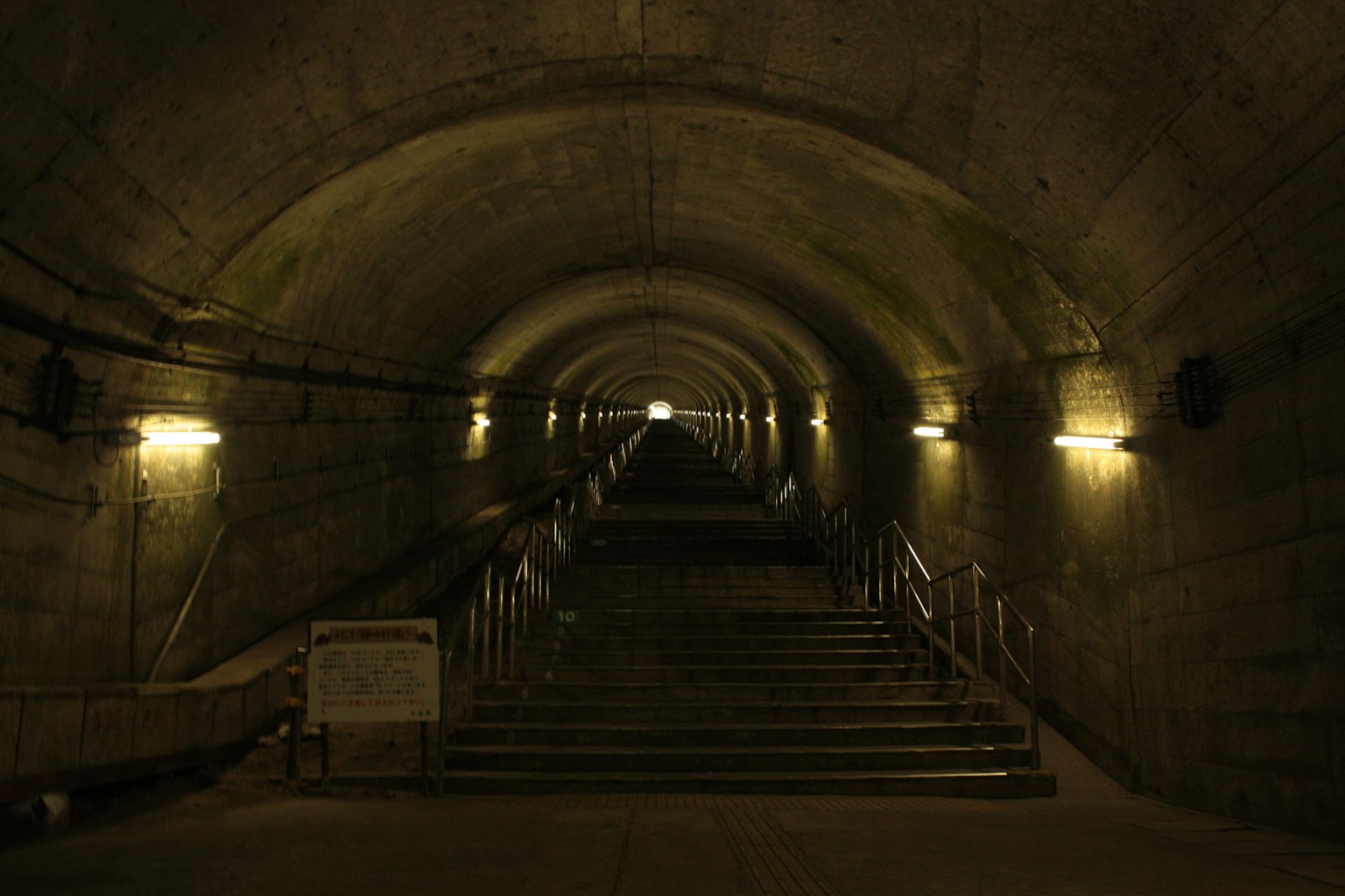 Innenansicht eines dunklen Tunnels mit Treppen und Beleuchtung