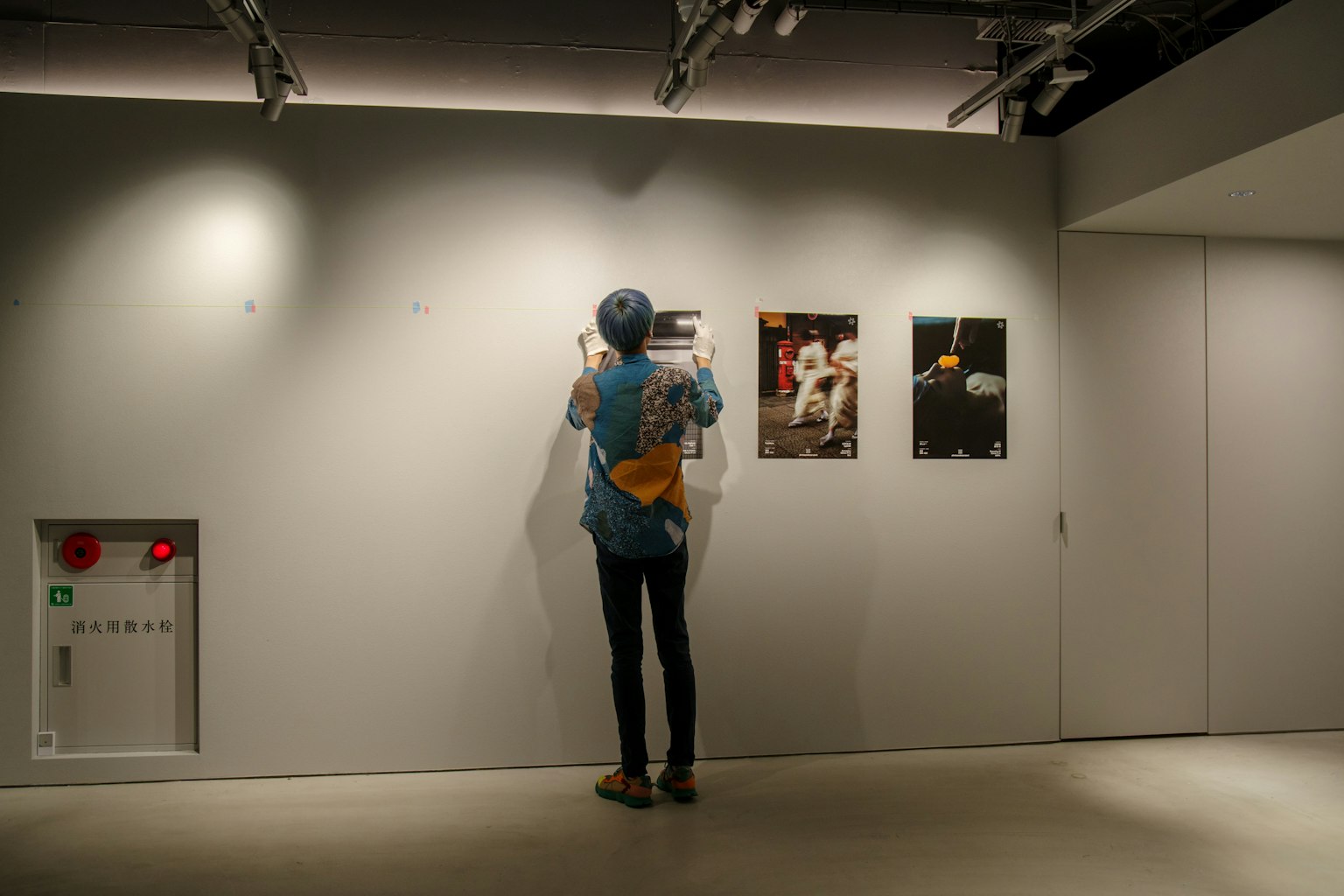 Người đang xem ảnh trên tường triển lãm trong không gian triển lãm tối giản