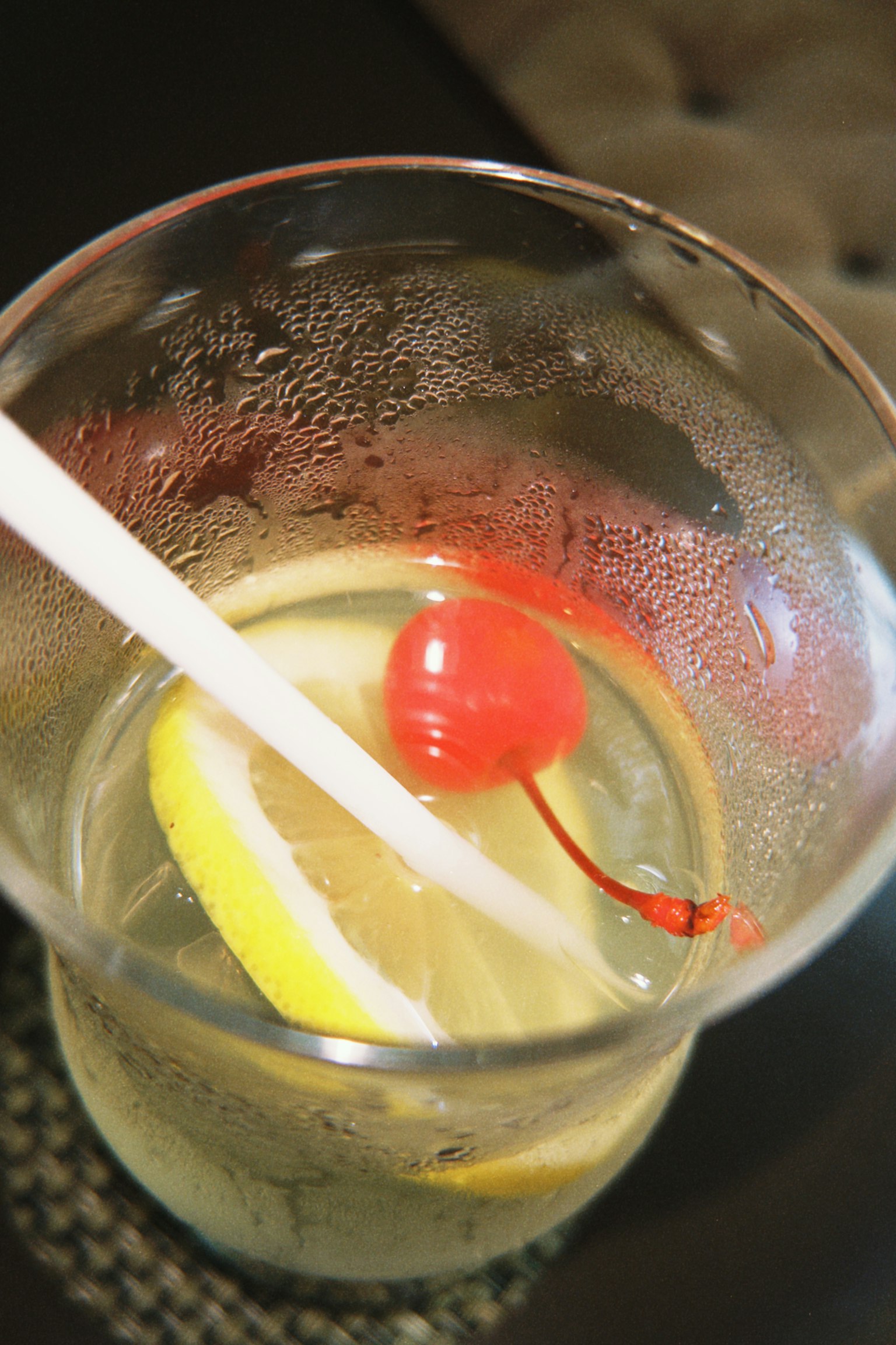 透明玻璃杯中的雞尾酒，配有冰塊、檸檬片和櫻桃