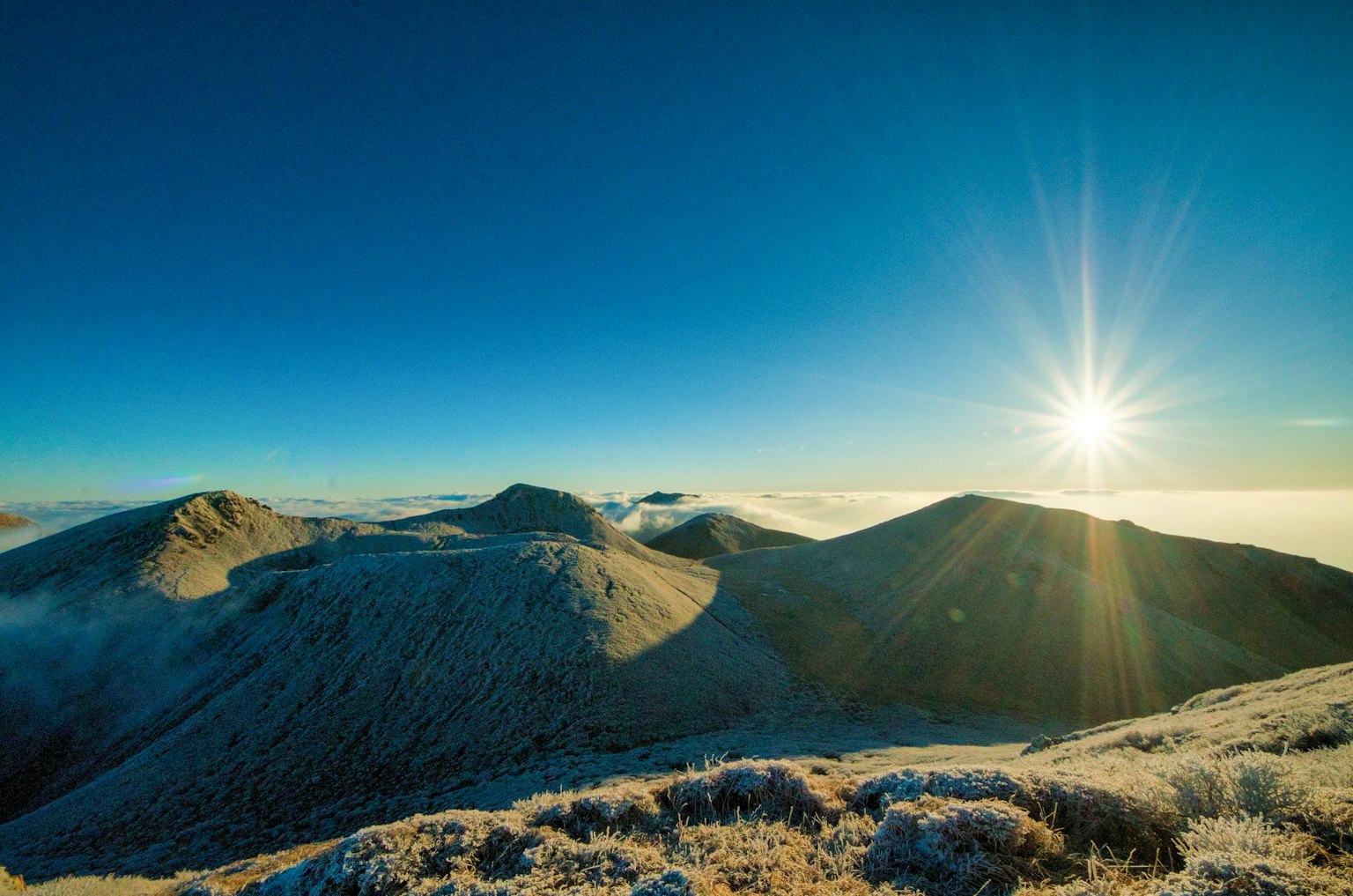Montagne coperte di neve sotto un cielo blu chiaro con un sole splendente