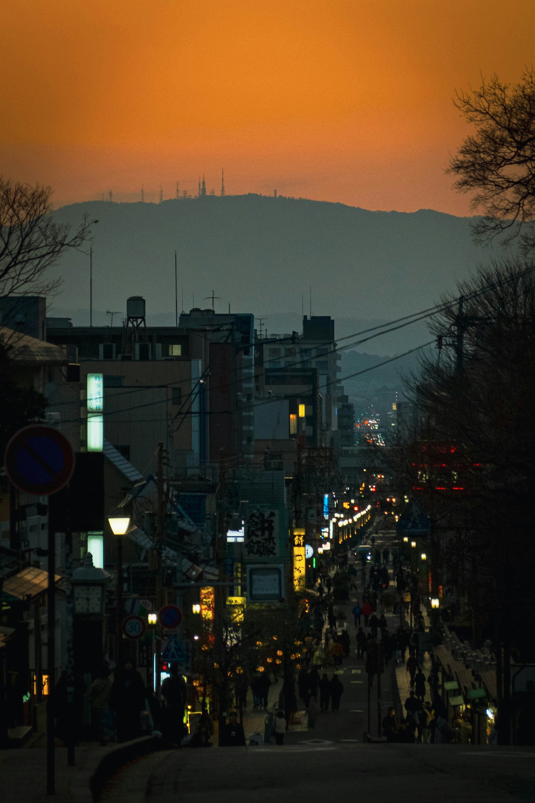 夕焼けの空と街灯が灯る坂道の商店街の夜景