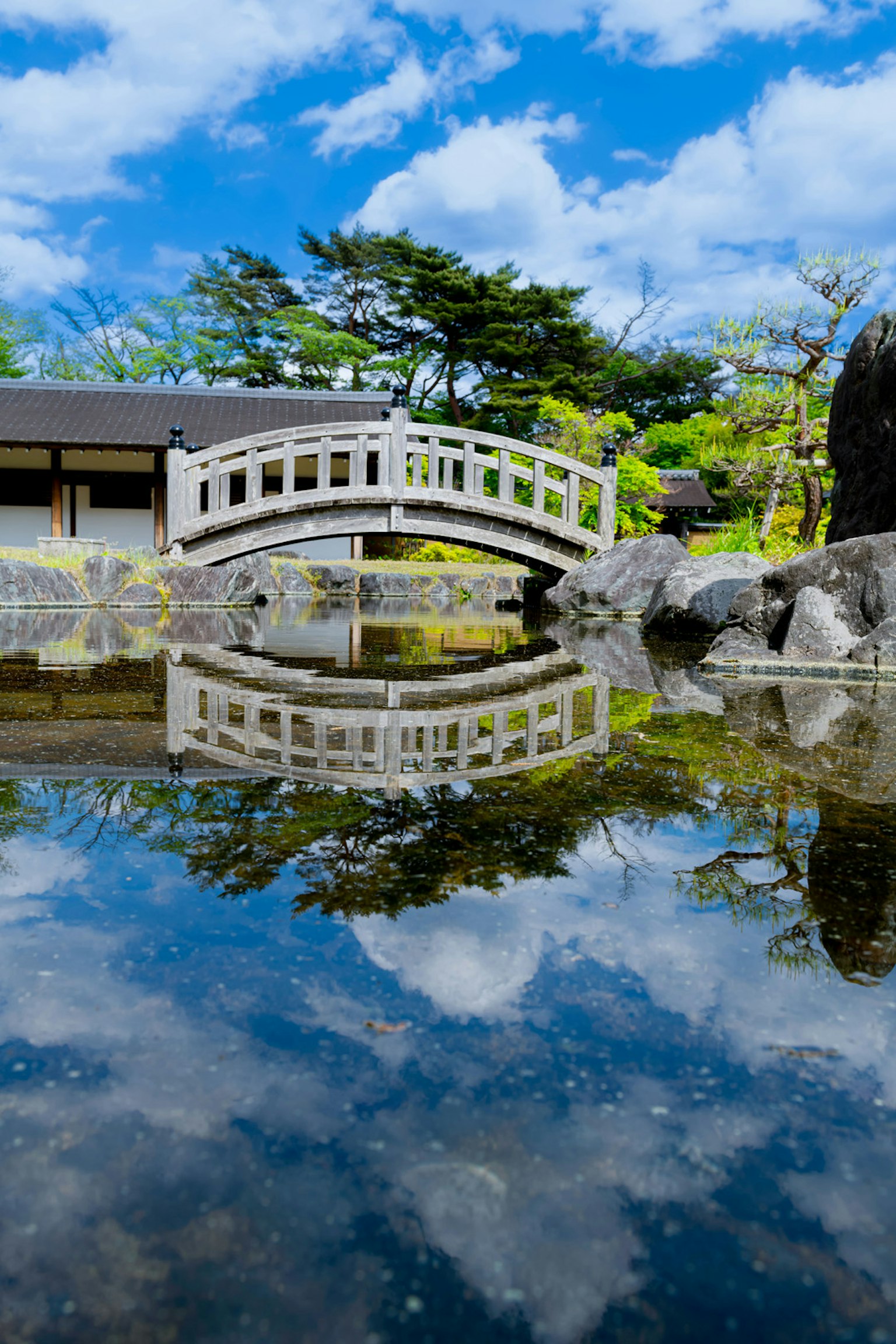 Vista escénica de un puente de jardín reflejándose en el agua