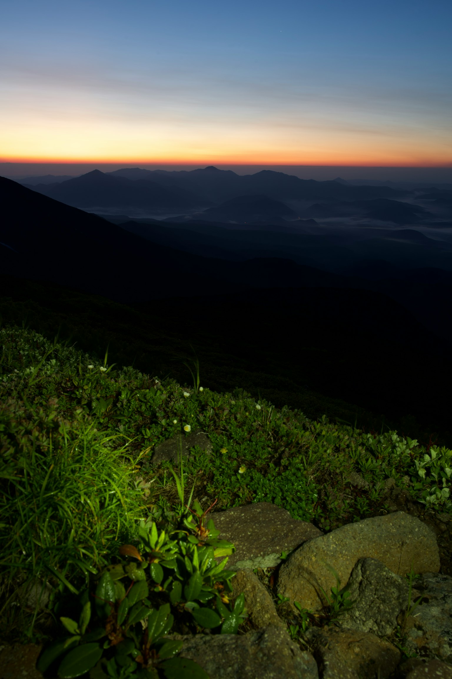 日落時的山景前景有草和岩石