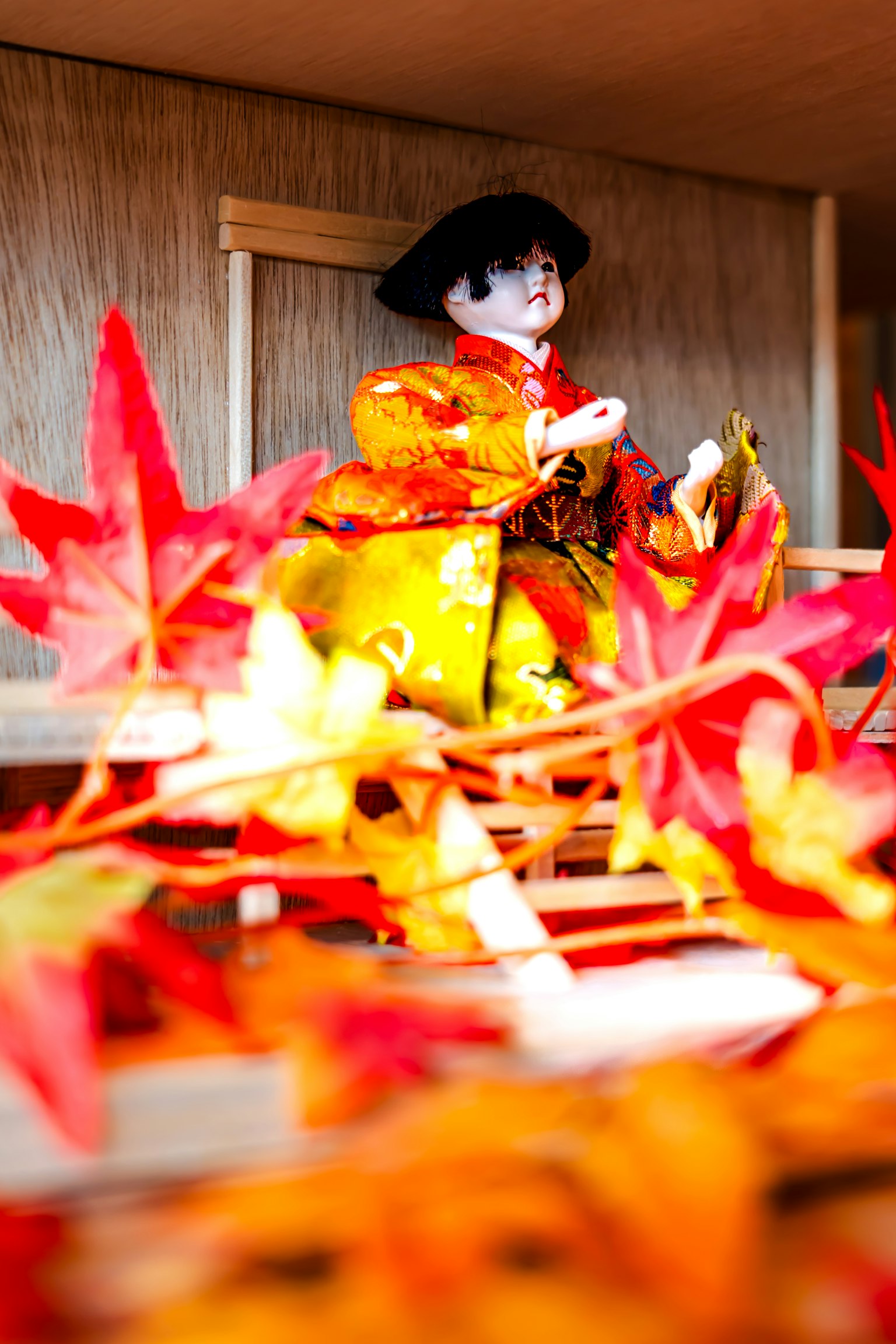 ตุ๊กตานั่งอยู่ท่ามกลางใบไม้ฤดูใบไม้ร่วงที่มีสีสันสดใส