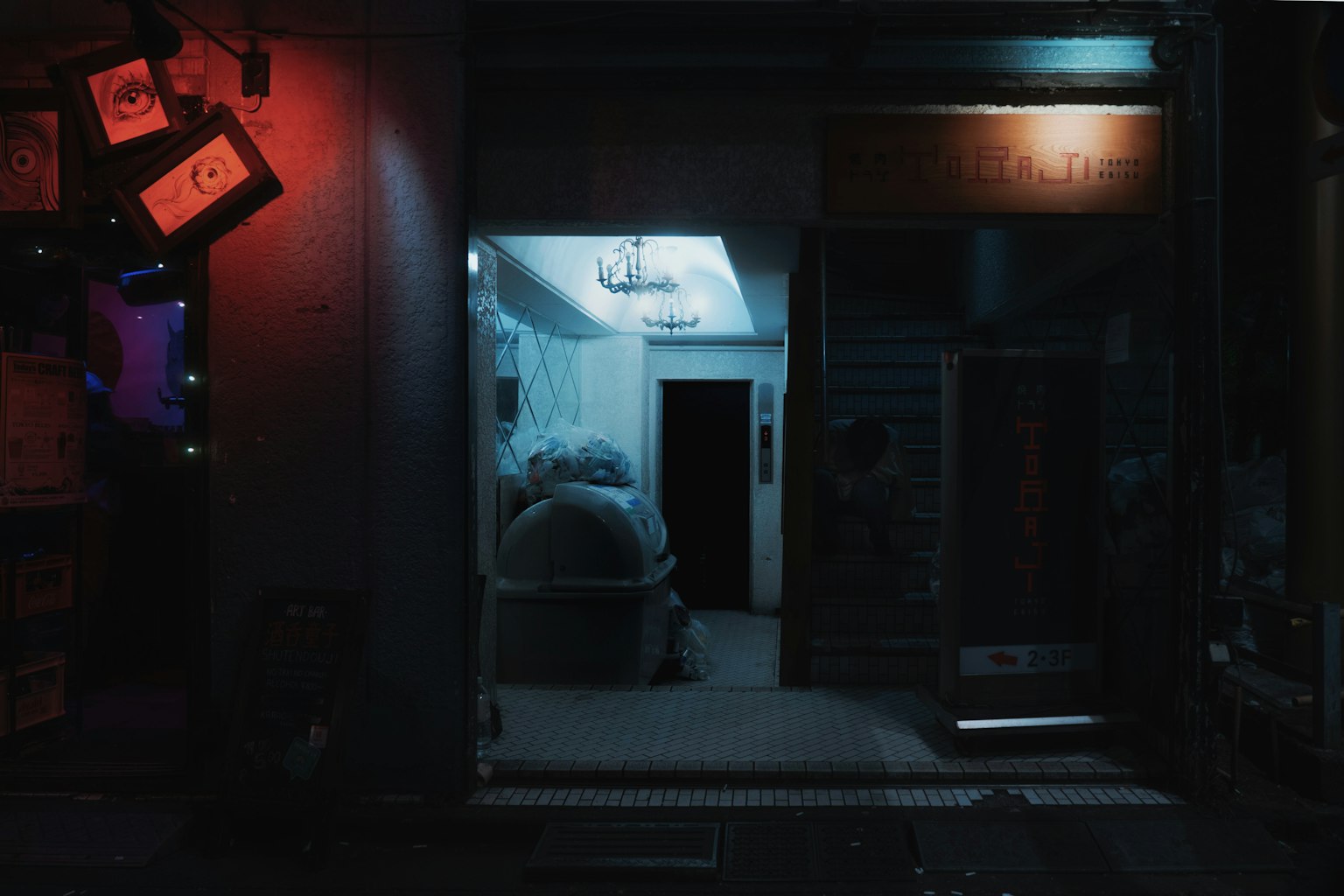 Entrada de la tienda con iluminación azul y roja en una calle oscura