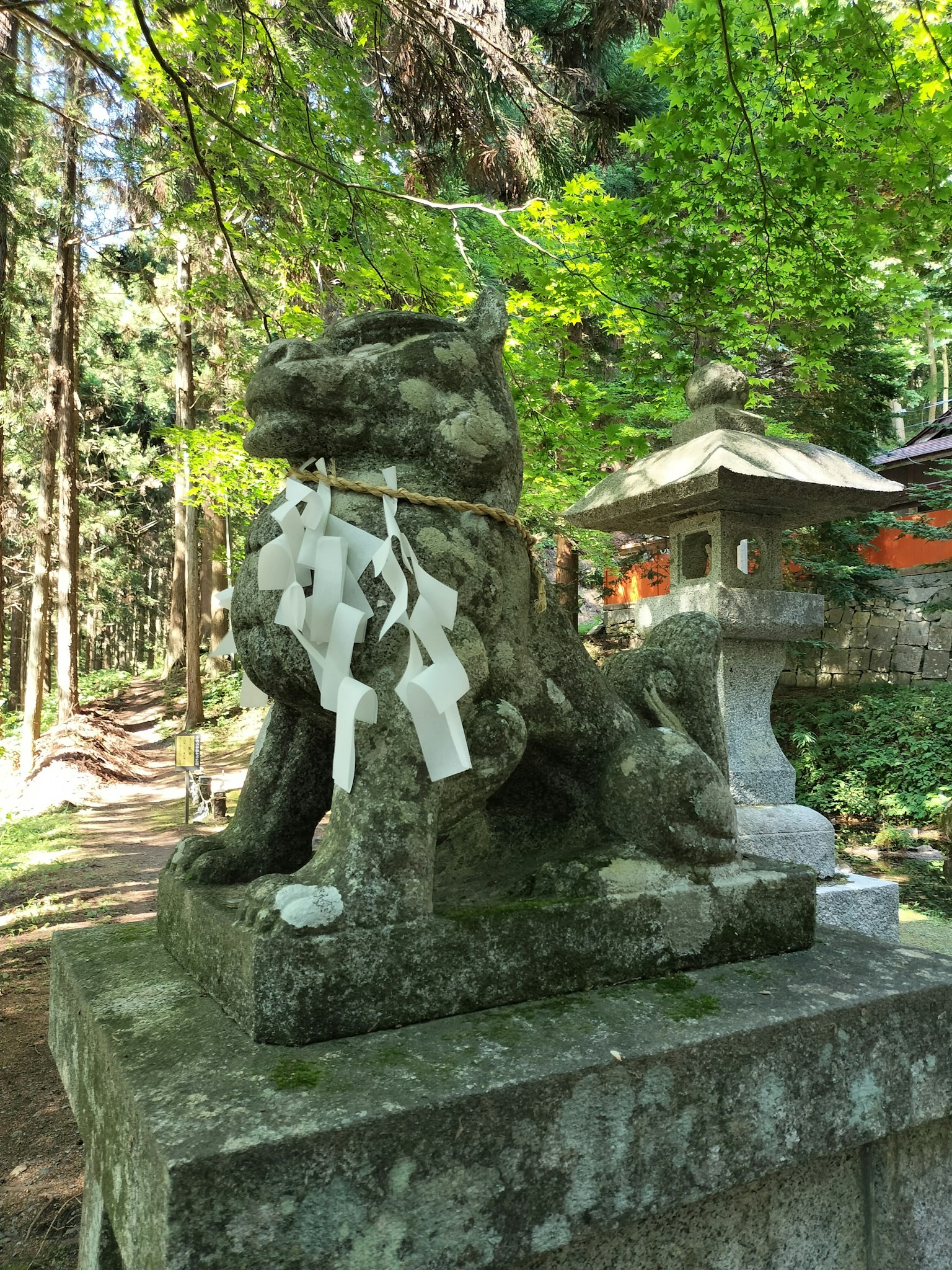Stone statue of a guardian lion in a forest with white shide