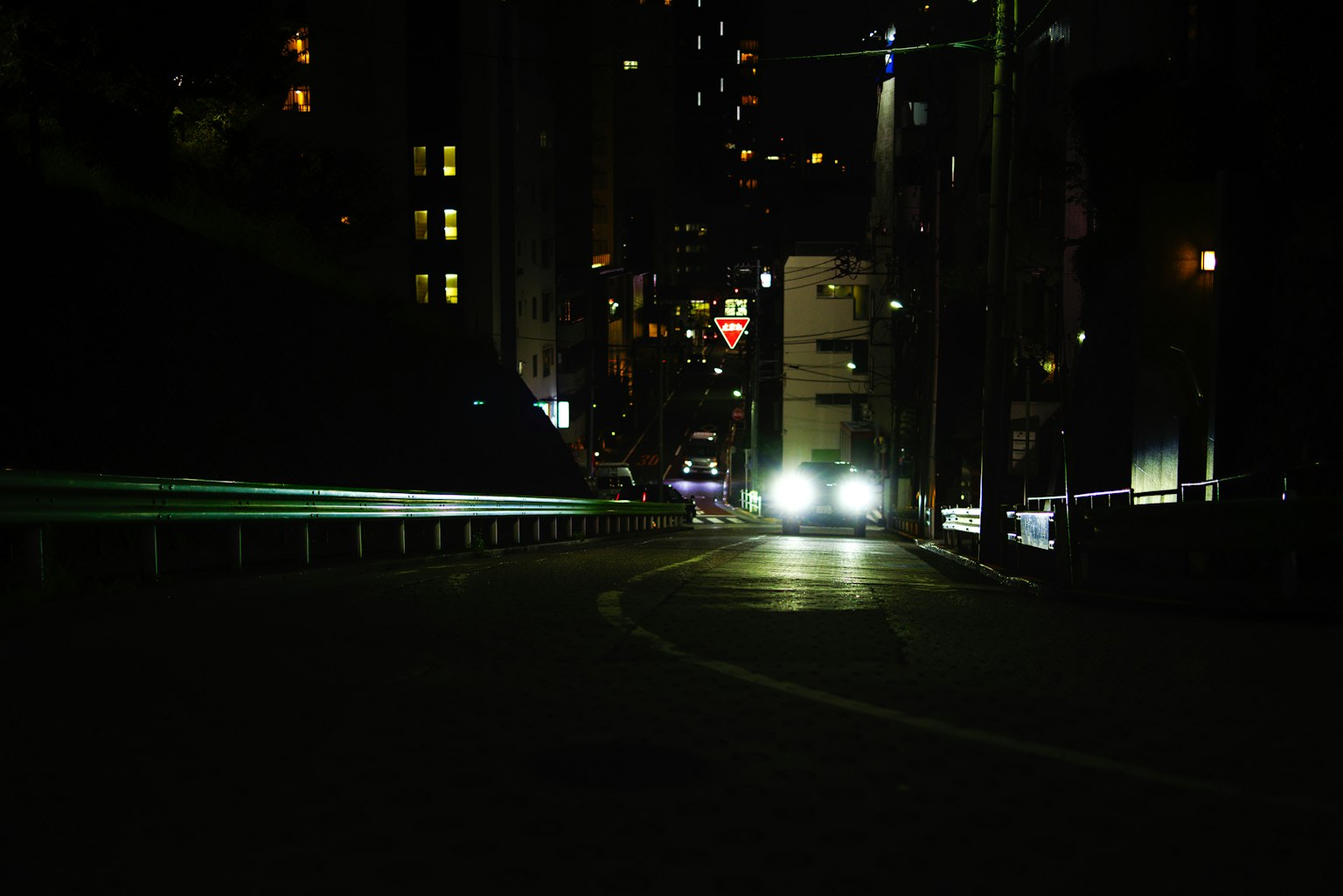 I fari di un'auto brillano su una strada urbana buia di notte