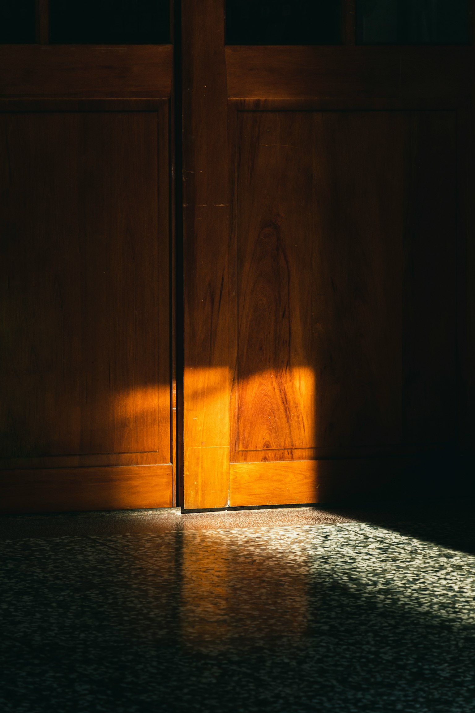 木製のドアの隙間から差し込む光と床の反射