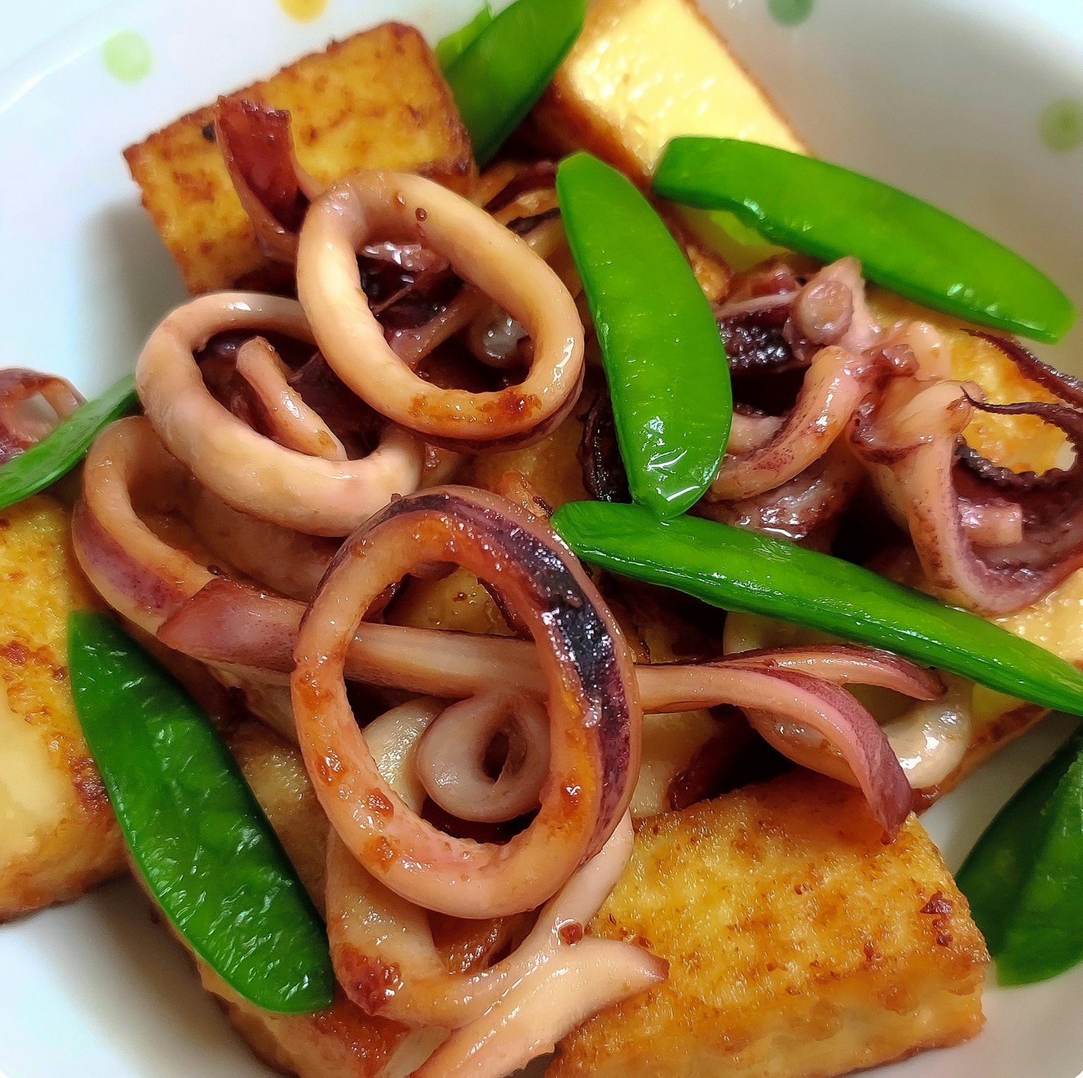 Tofu salteado con calamares y guisantes en un plato