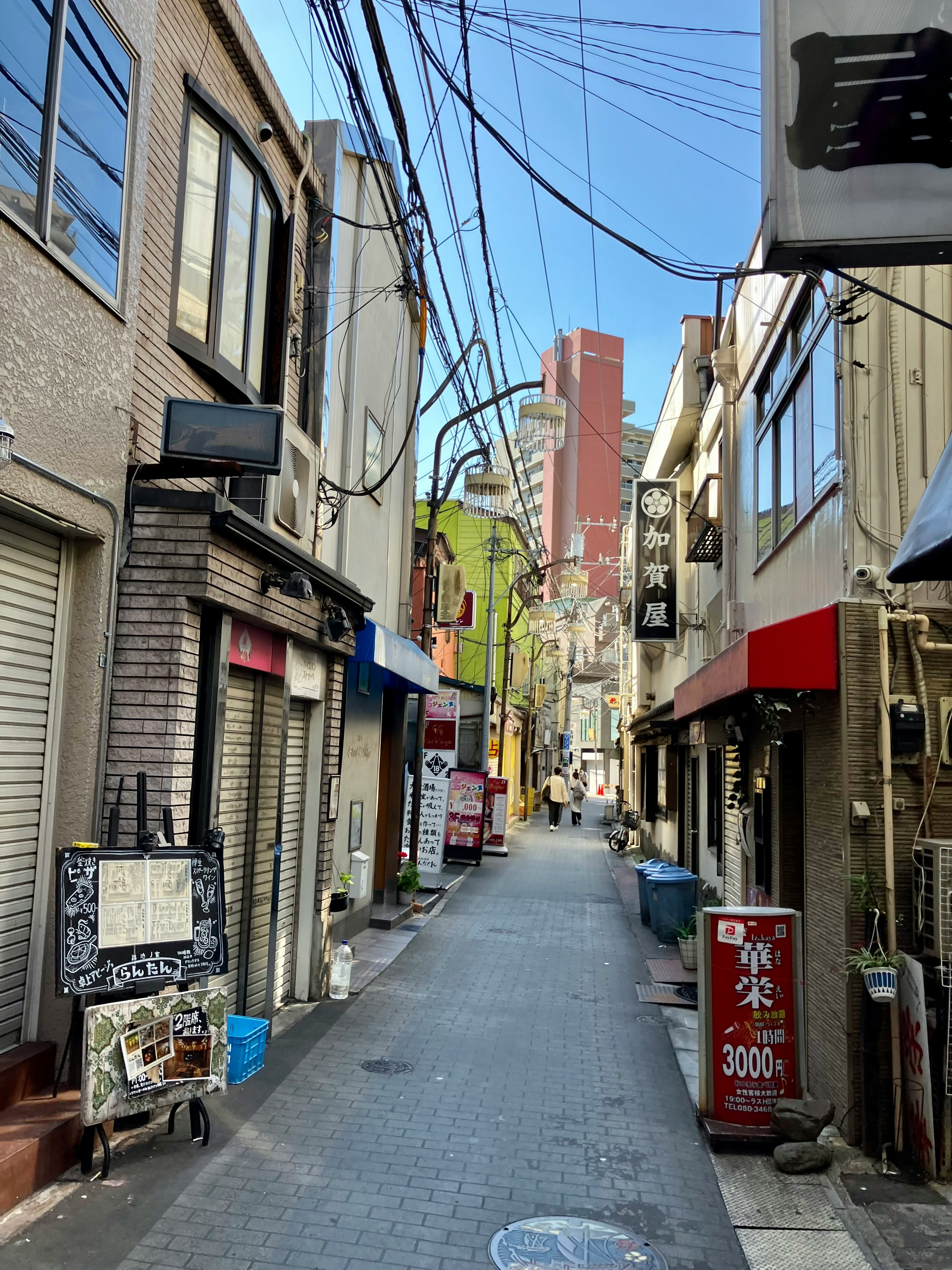 朝の飲み屋街の路地に並ぶ店先と青空