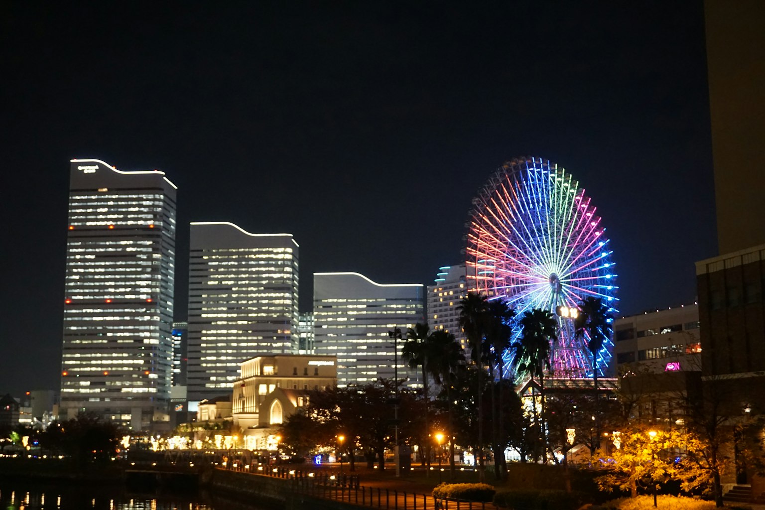 Night cityscape featuring a colorful Ferris wheel and skyscrapers