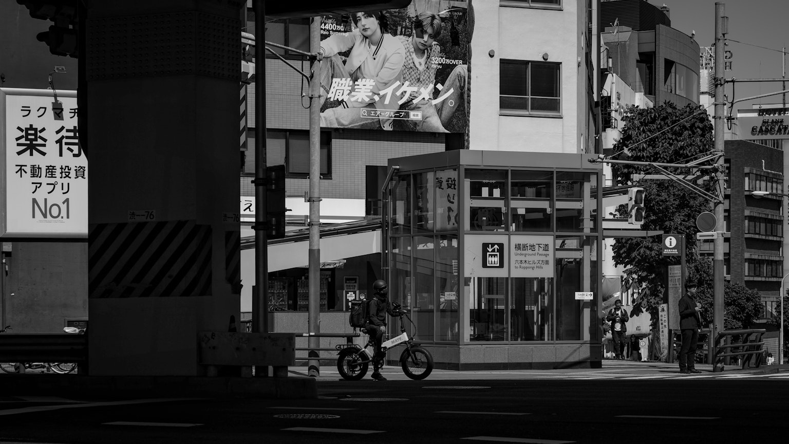 Street corner in Tokyo featuring a phone booth and buildings with a cyclist passing by