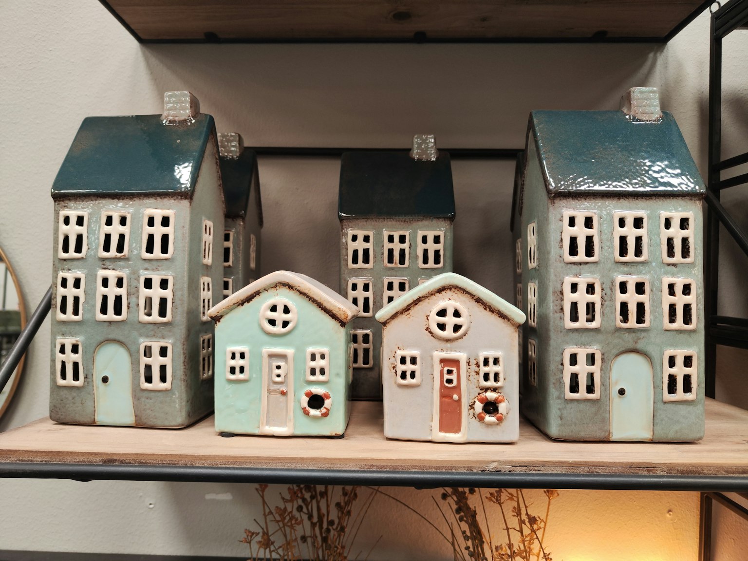 Una collezione di case in ceramica con tetti blu esposte su uno scaffale