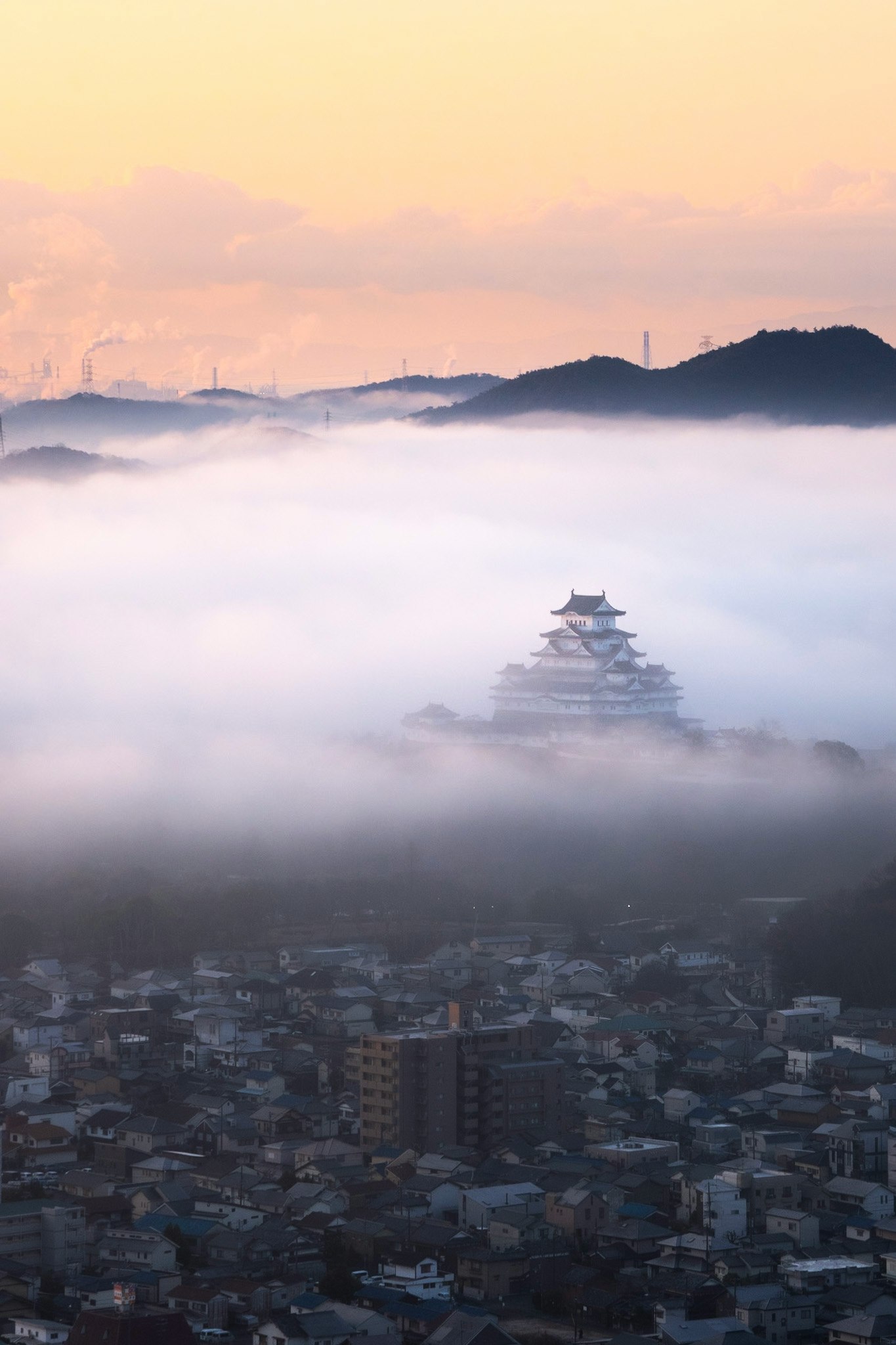 霧に包まれた街と遠くの城郭風の塔