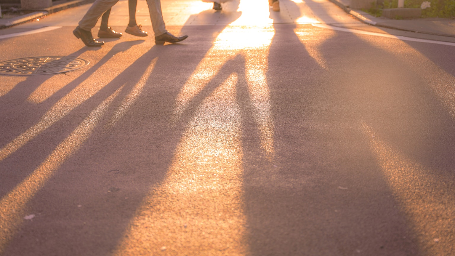 Silhouettes of people walking at sunset on a city street