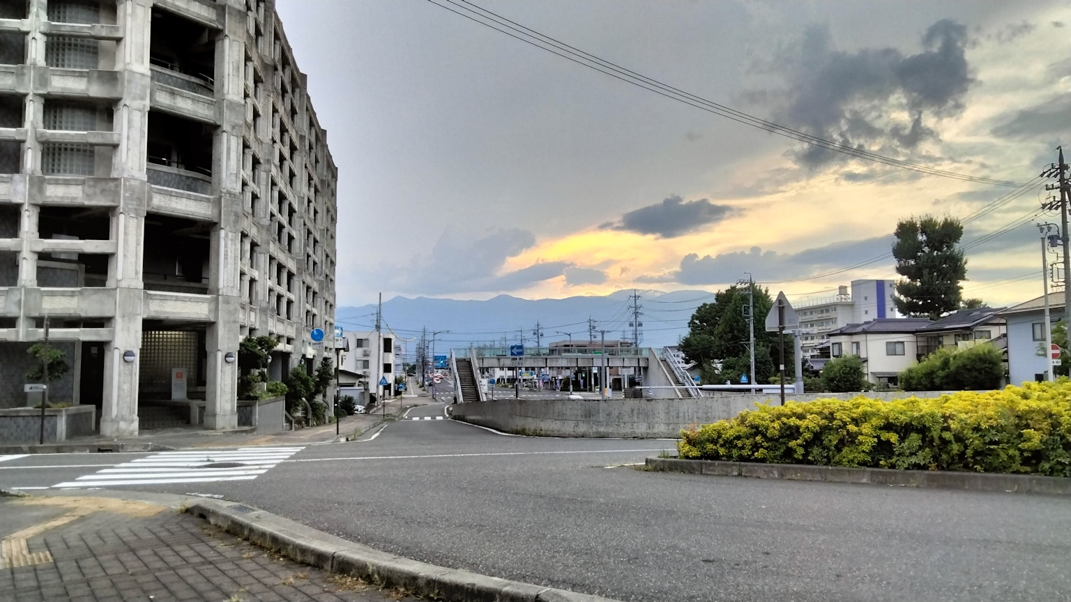 Urban street view under cloudy sky with distant mountains