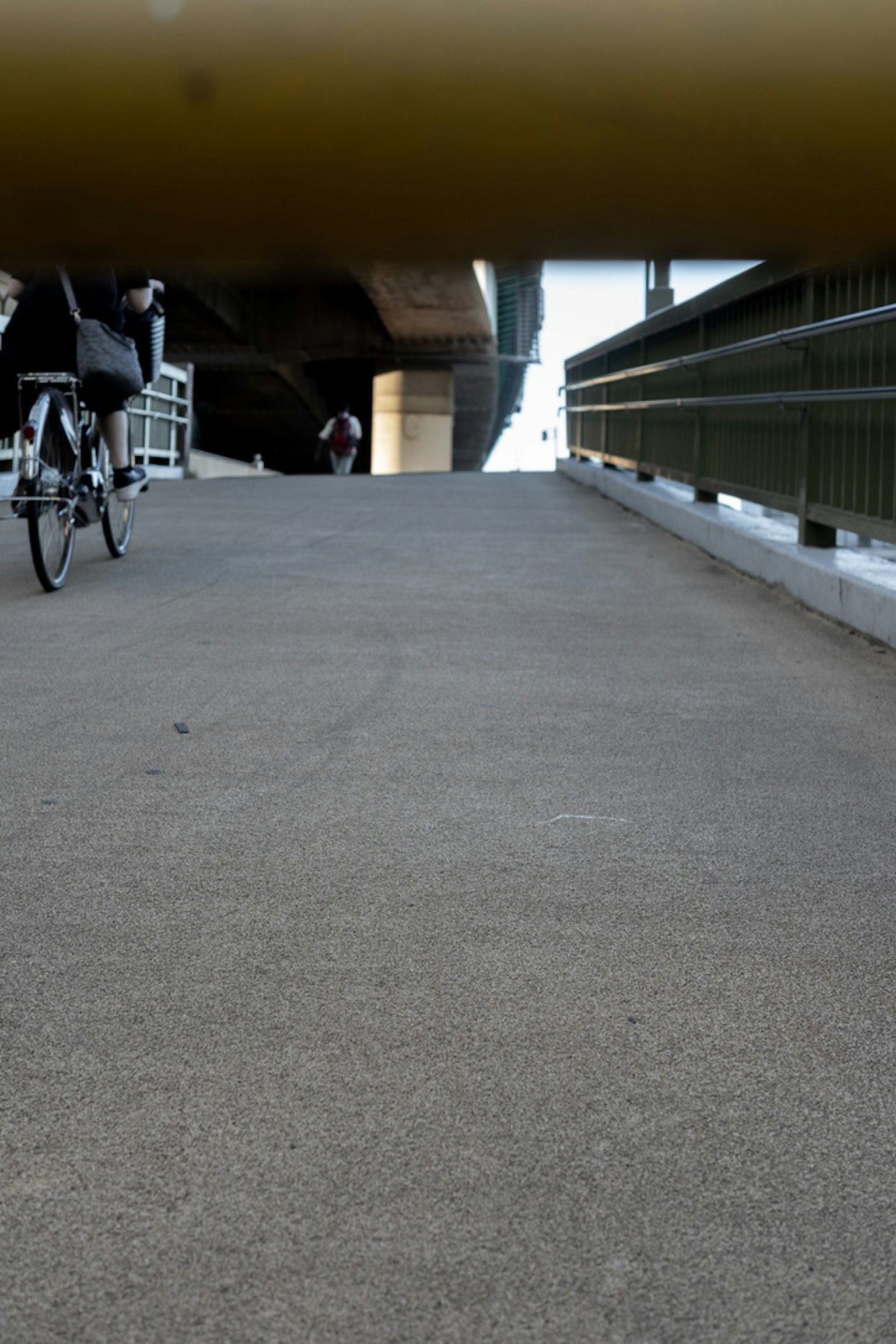 Blick auf einen gepflasterten Weg aus der Sicht eines Radfahrers unter einer Brücke
