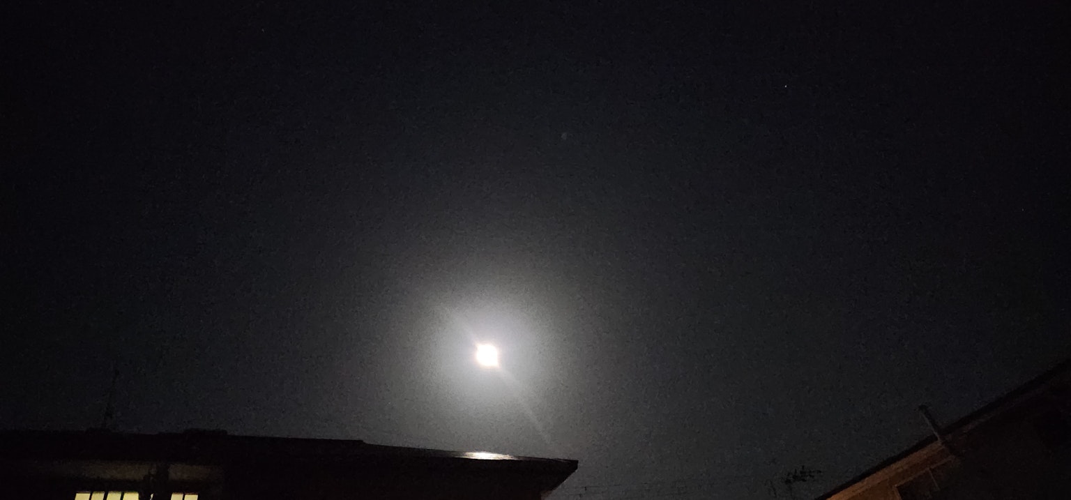 夜空中明亮的月亮与黑暗的建筑轮廓